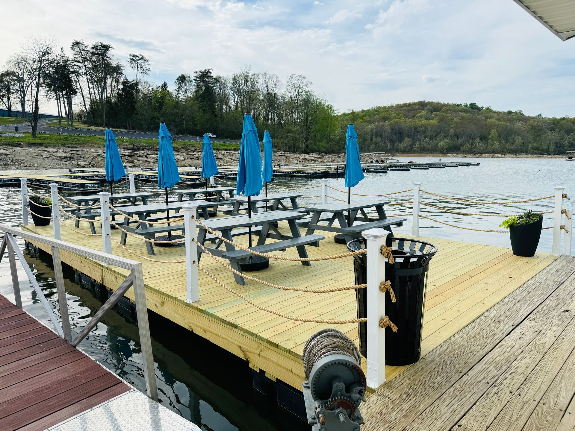 A wooden dock with picnic tables and umbrellas on it.