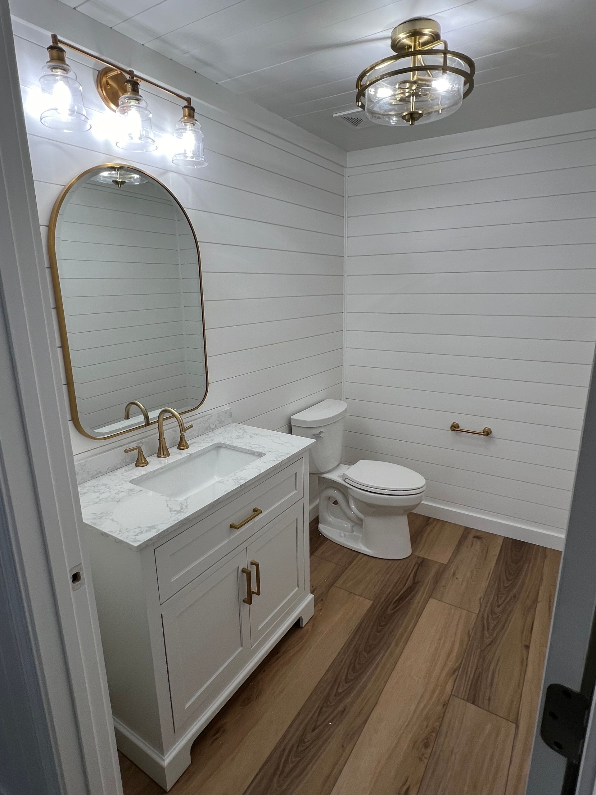 A bathroom with a sink , toilet , mirror and ceiling fan.