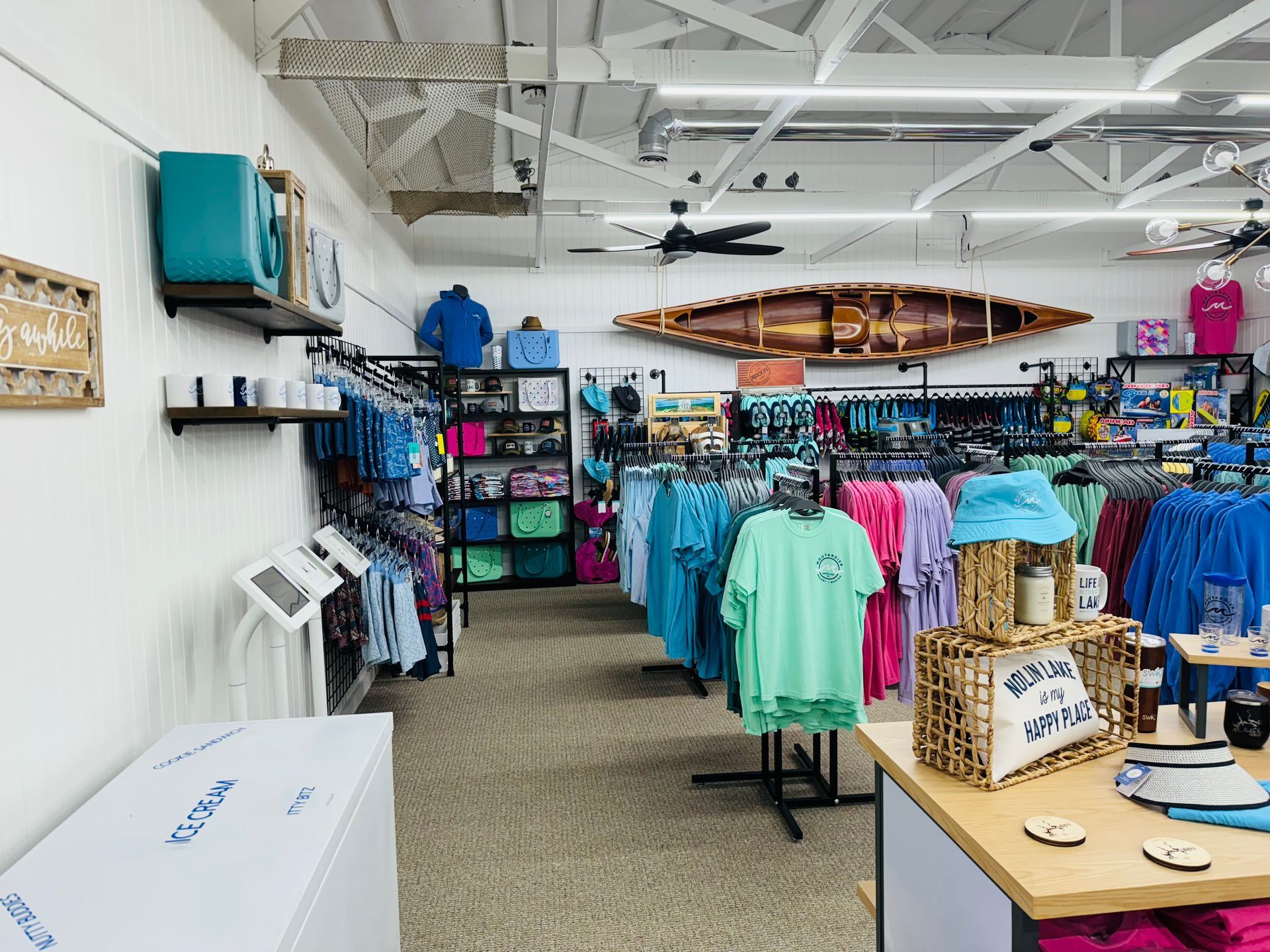 A store filled with lots of clothes and a canoe on the wall.
