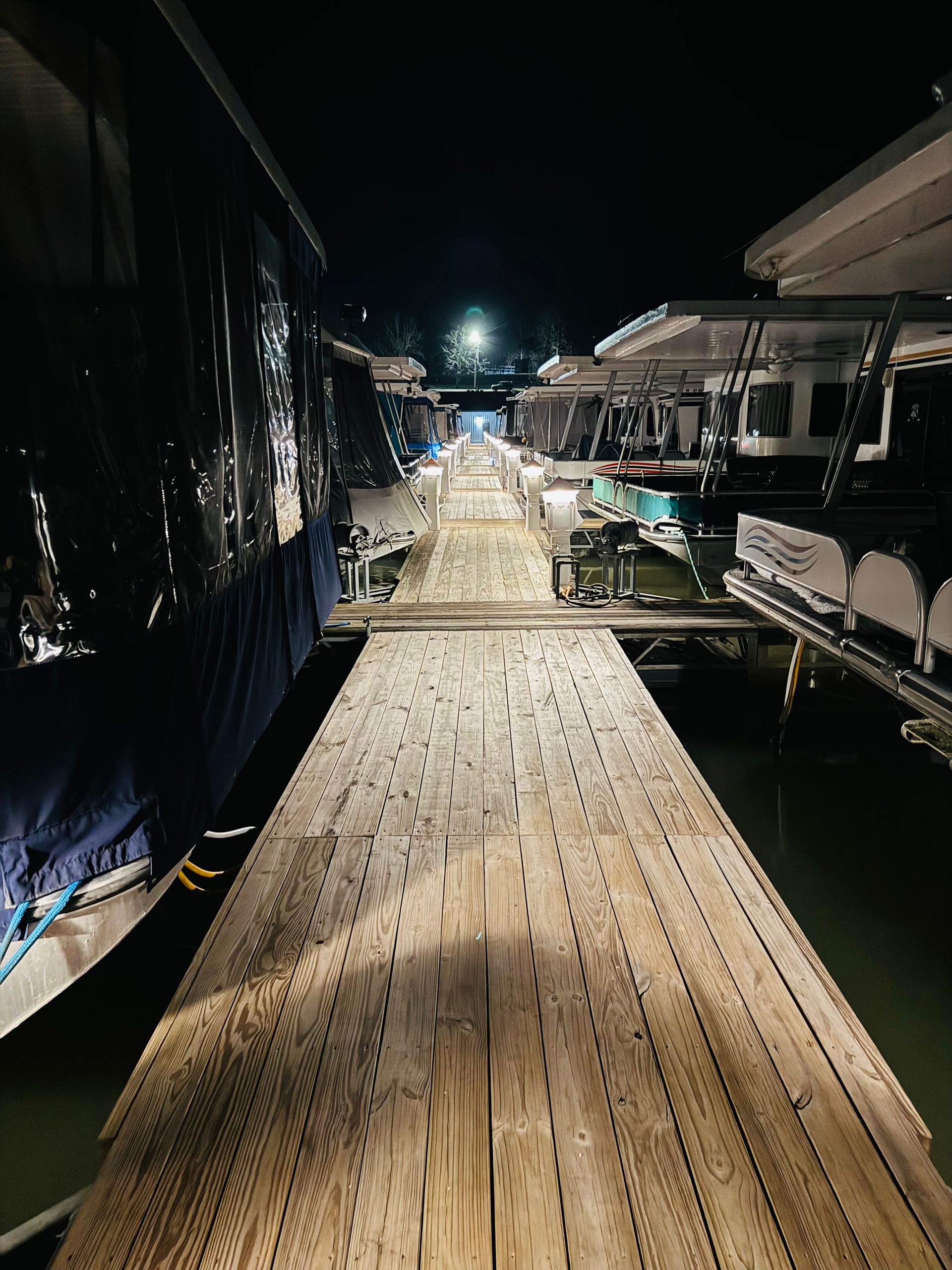A wooden dock with boats docked on it at night.
