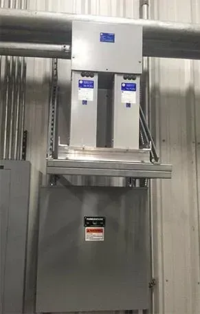 A large electrical box is hanging from the ceiling of a building.