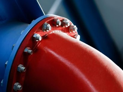 A close up of a red pipe with nuts and bolts on it