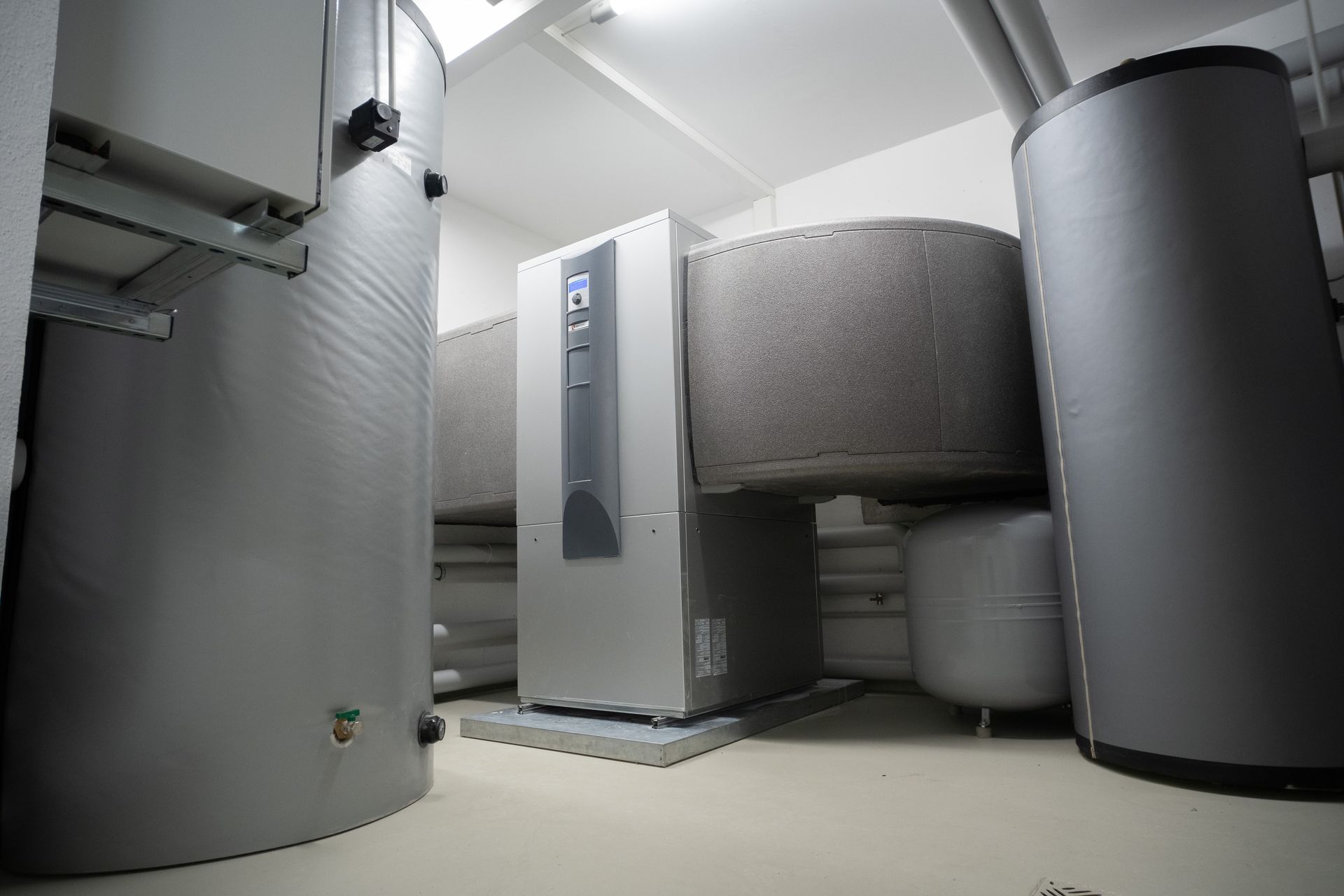 Industrial room with large metal tanks, pipes, and a central control unit