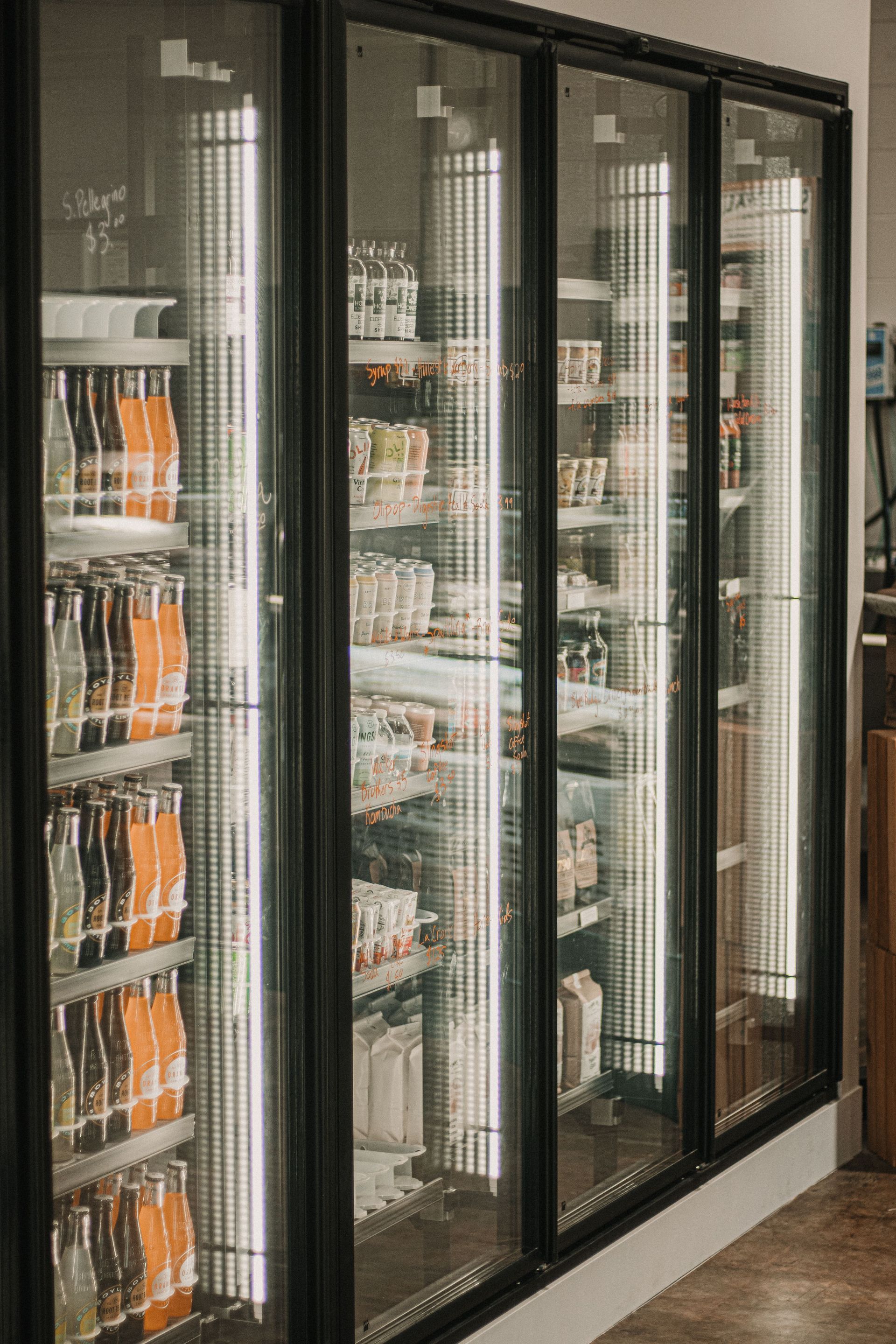 Glass-door refrigerated display case stocked with drinks in a store aisle