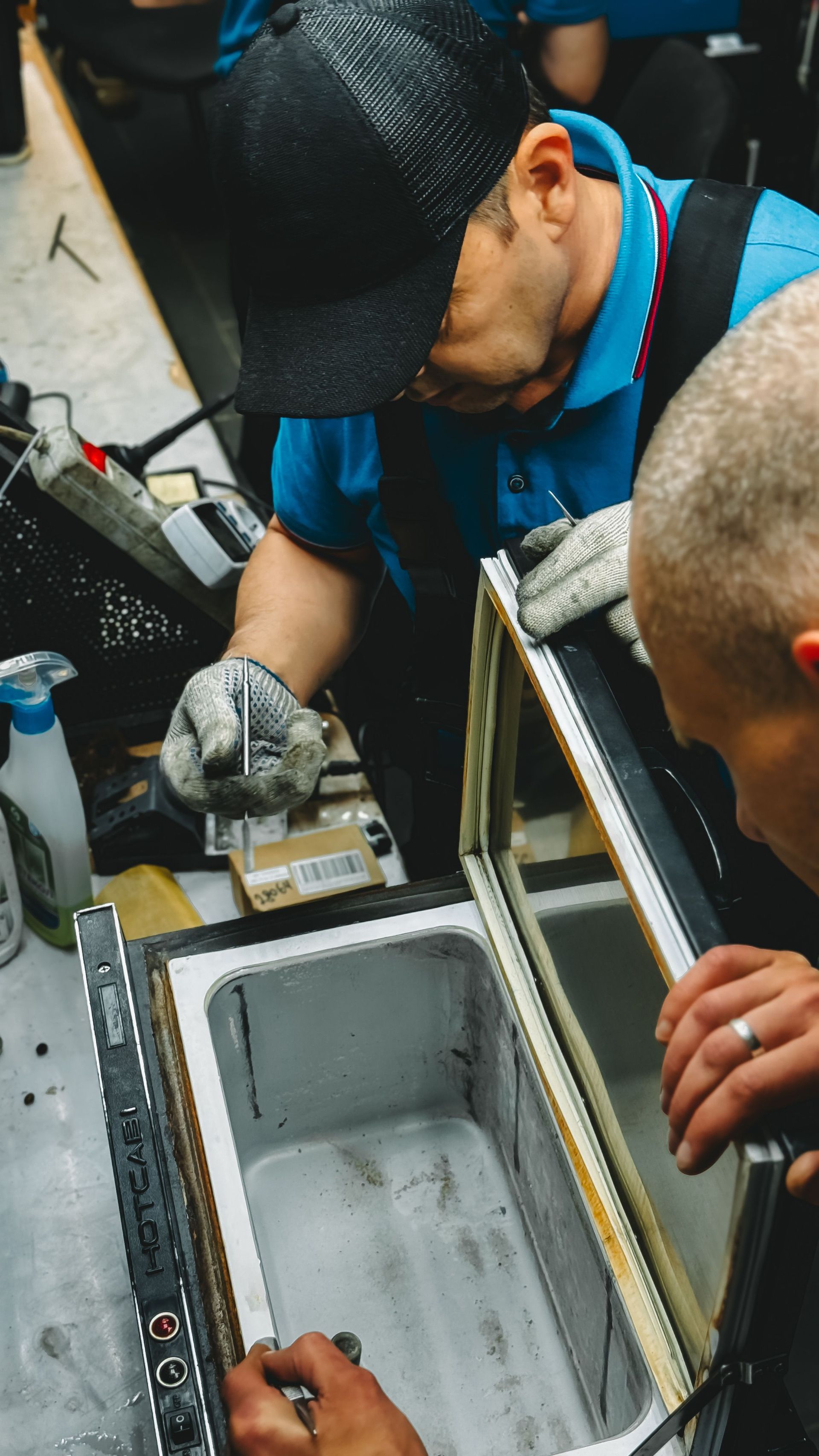 Technicians working over an open metal equipment case with tools and cables.