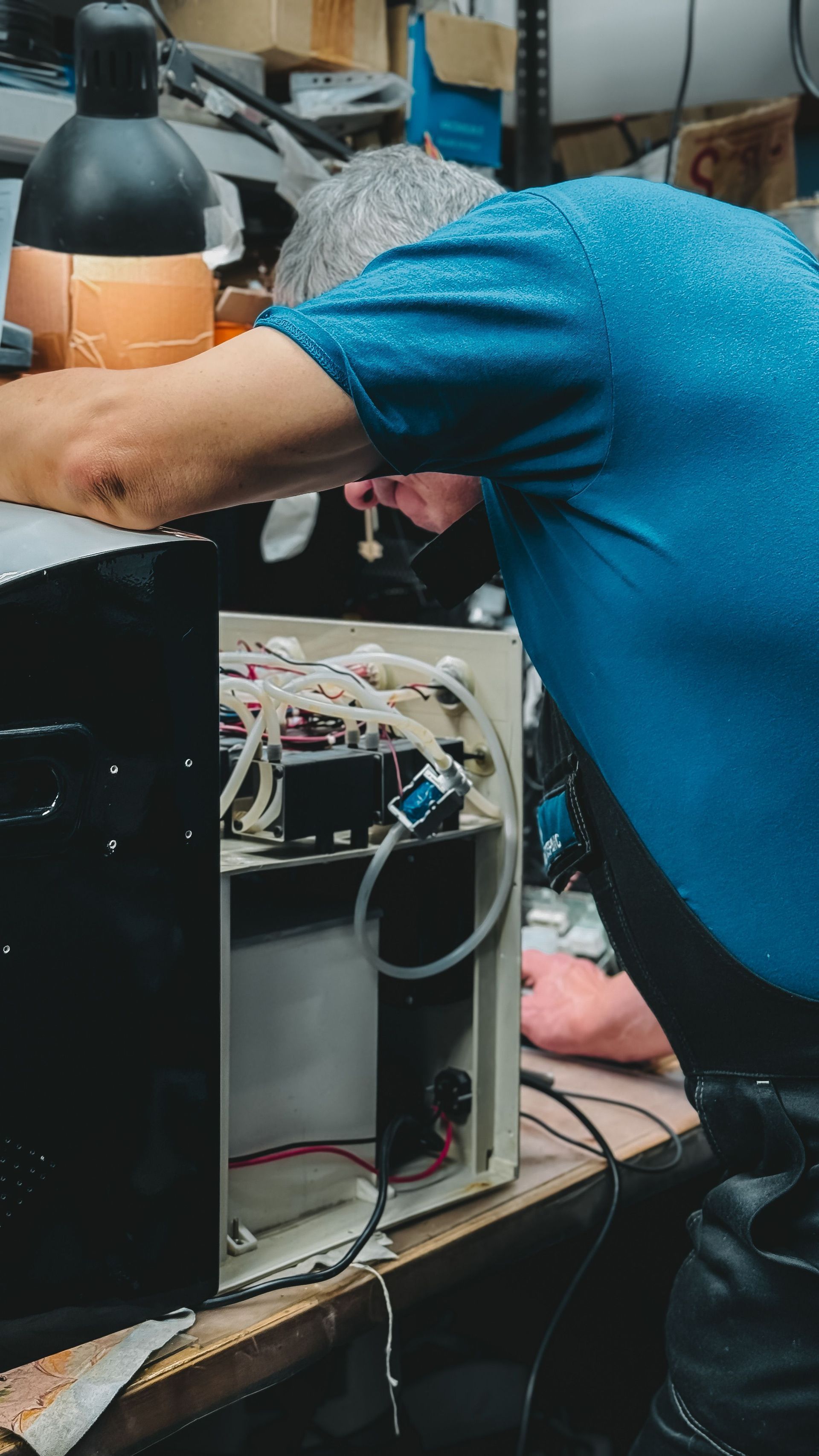 Technician working inside an open computer tower on a workbench, with tools and cables nearby