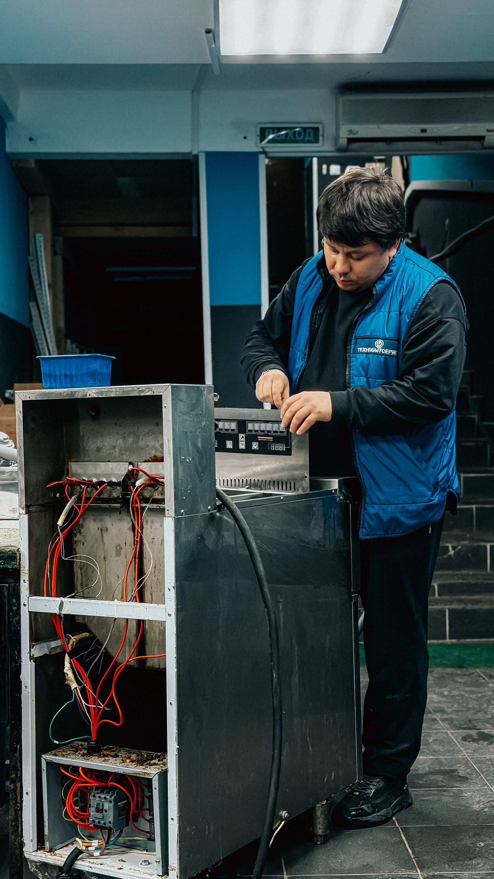 Technician adjusting equipment beside an open server rack in a workshop