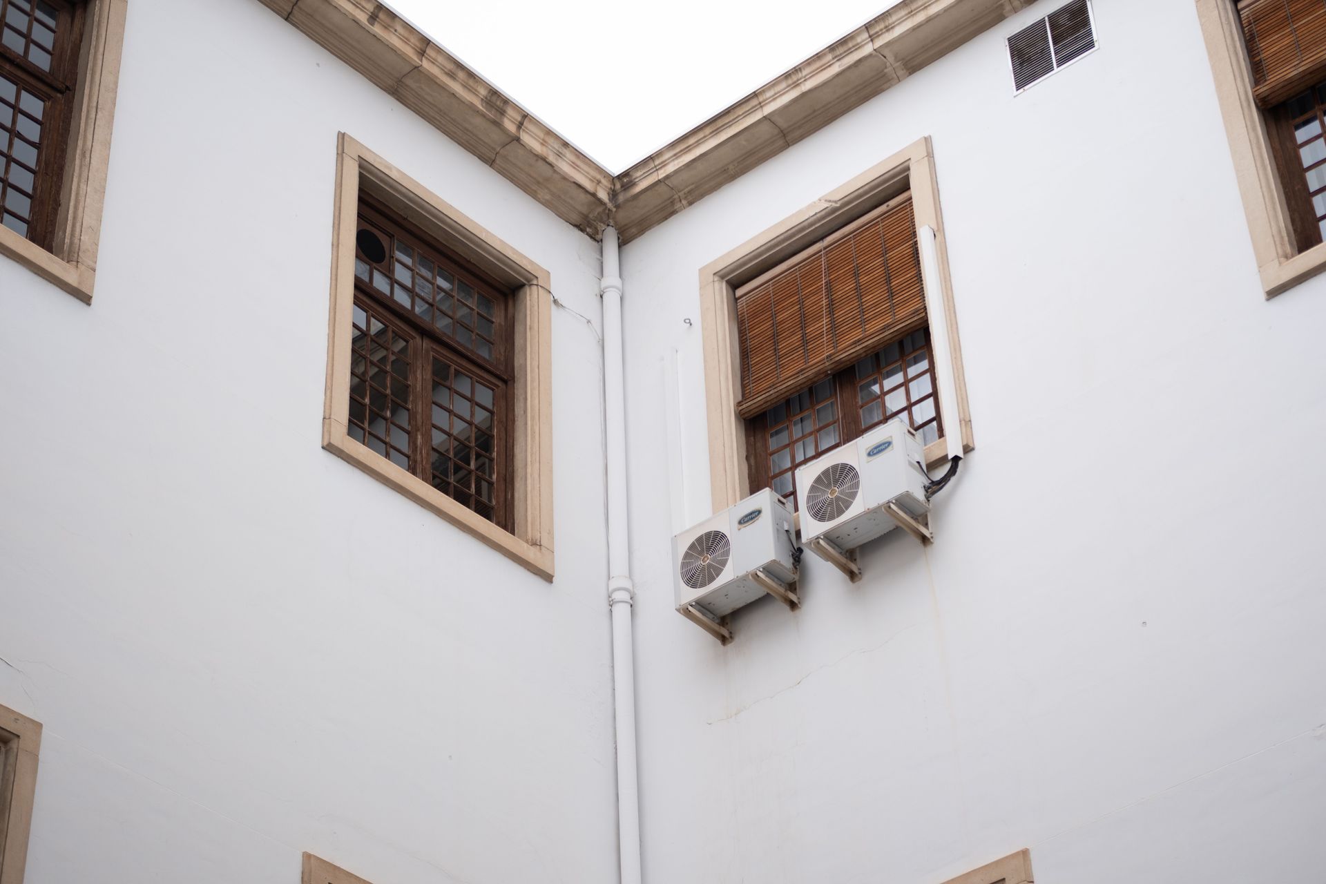 Courtyard corner with white walls, barred windows, and two wall-mounted air conditioners