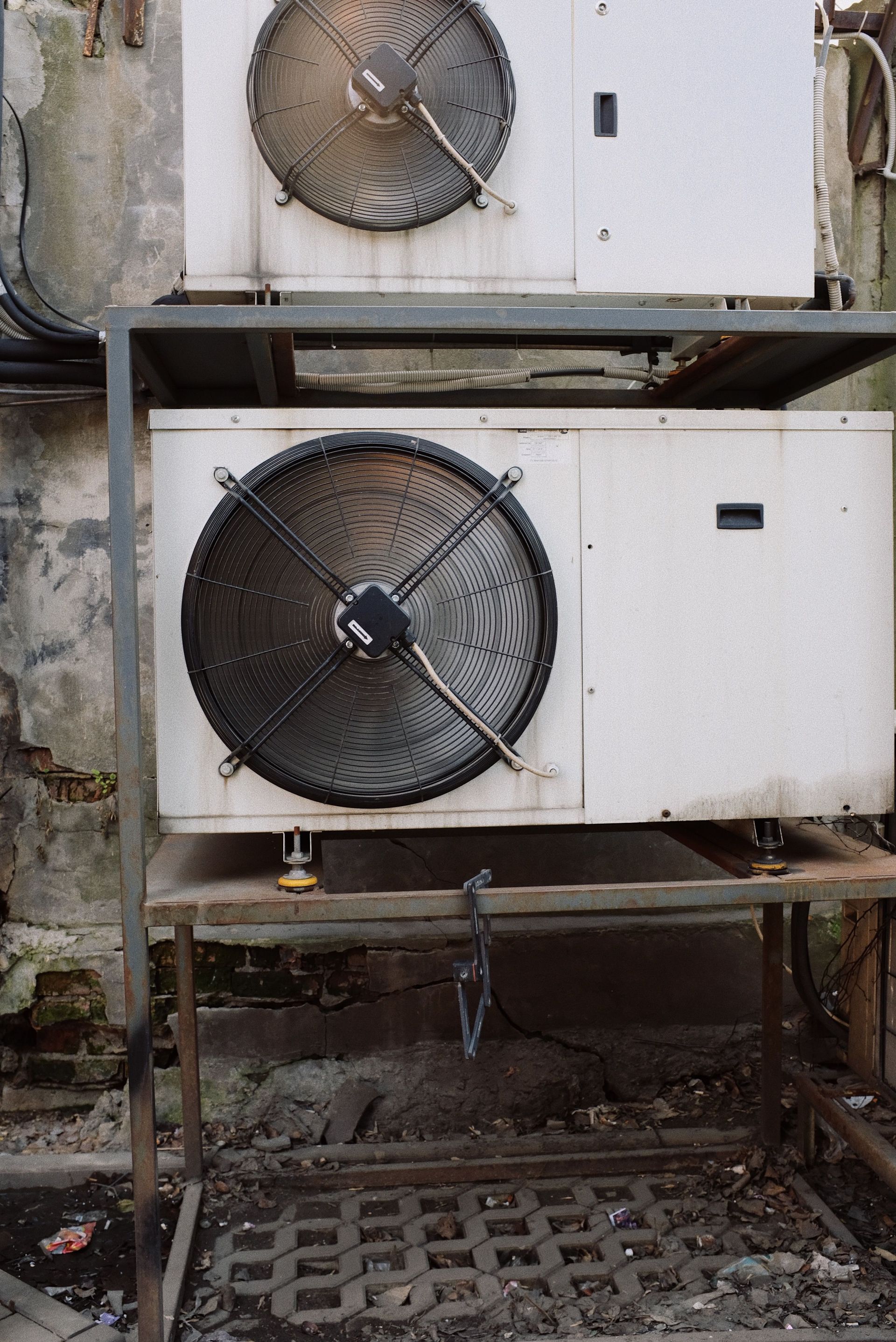 Industrial cooling units with large fans mounted on metal stands above a grated floor.