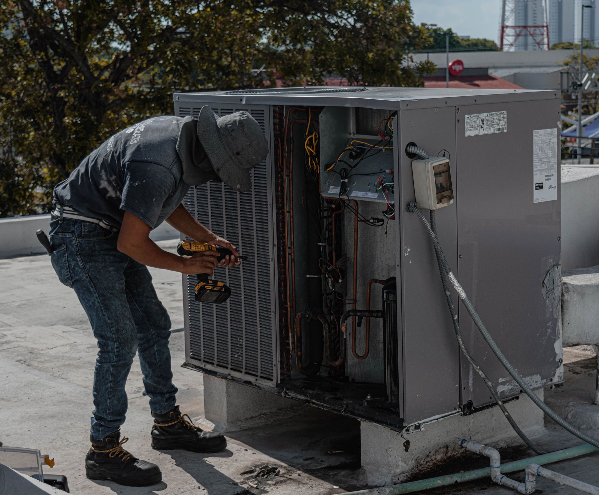 Technician working on an outdoor HVAC unit on a rooftop