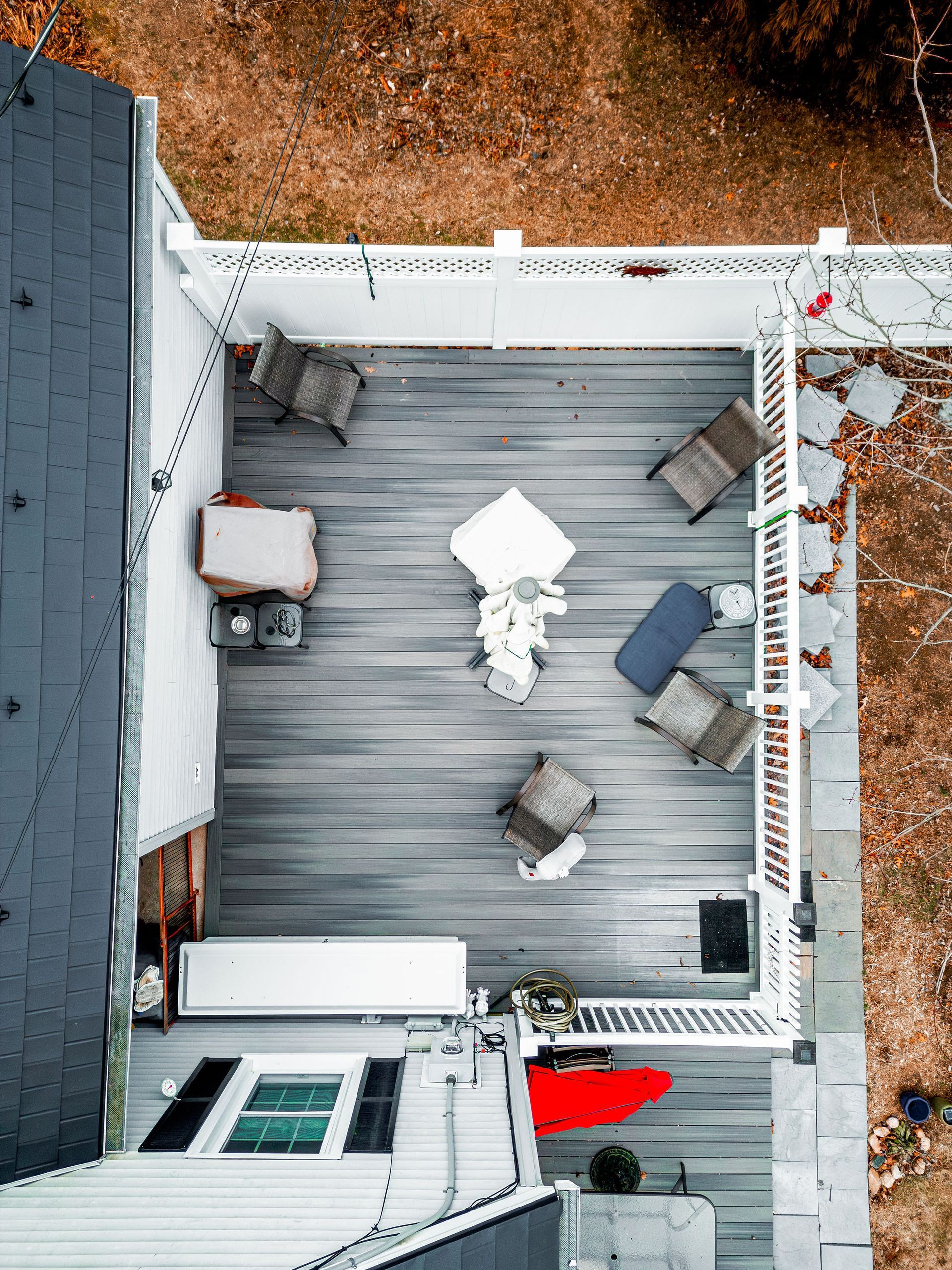 Overhead view of a gray wooden deck with white railing, furnished with chairs and a table.
