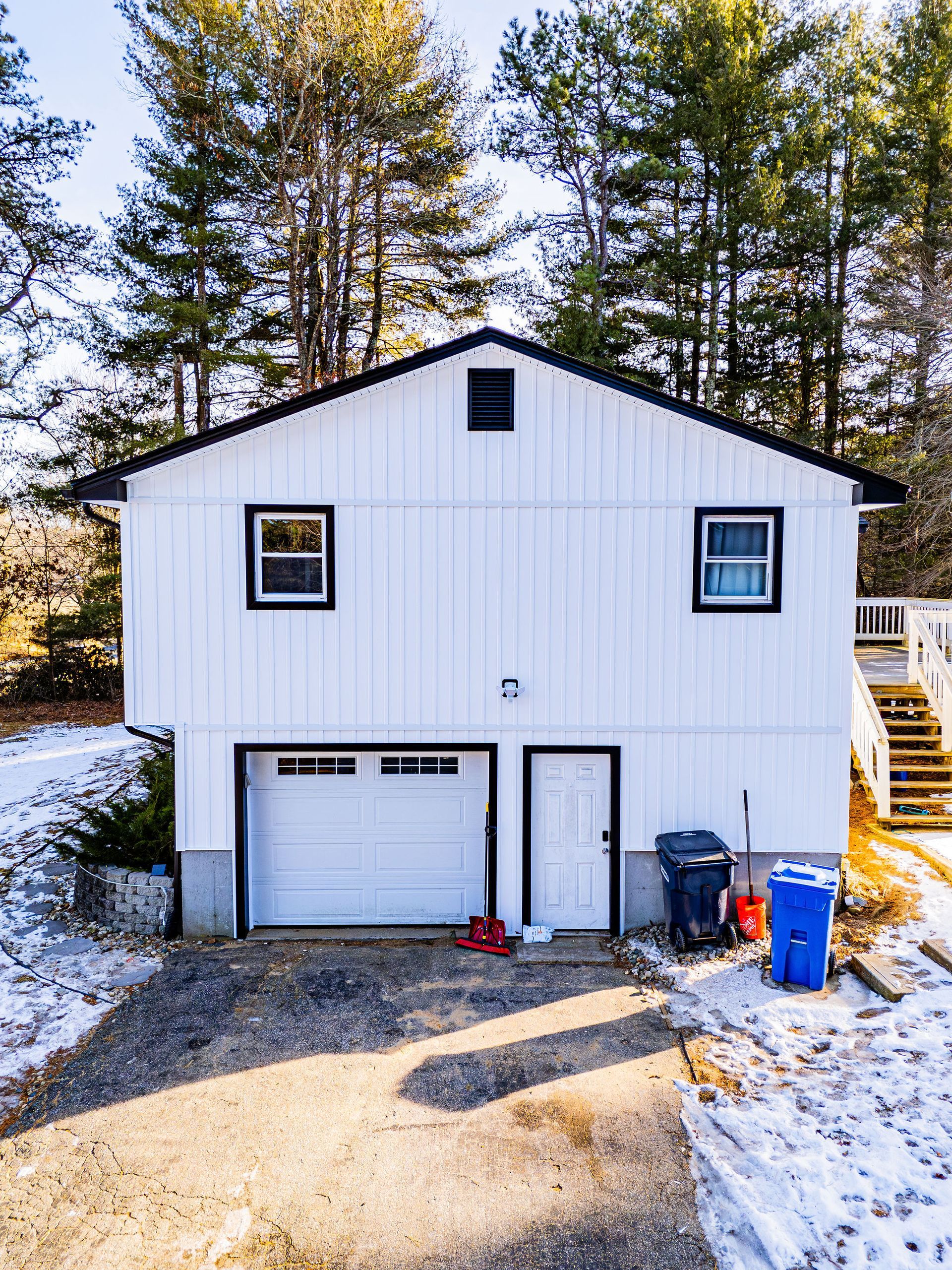White two-story house with a garage and driveway. Snow covers the ground.