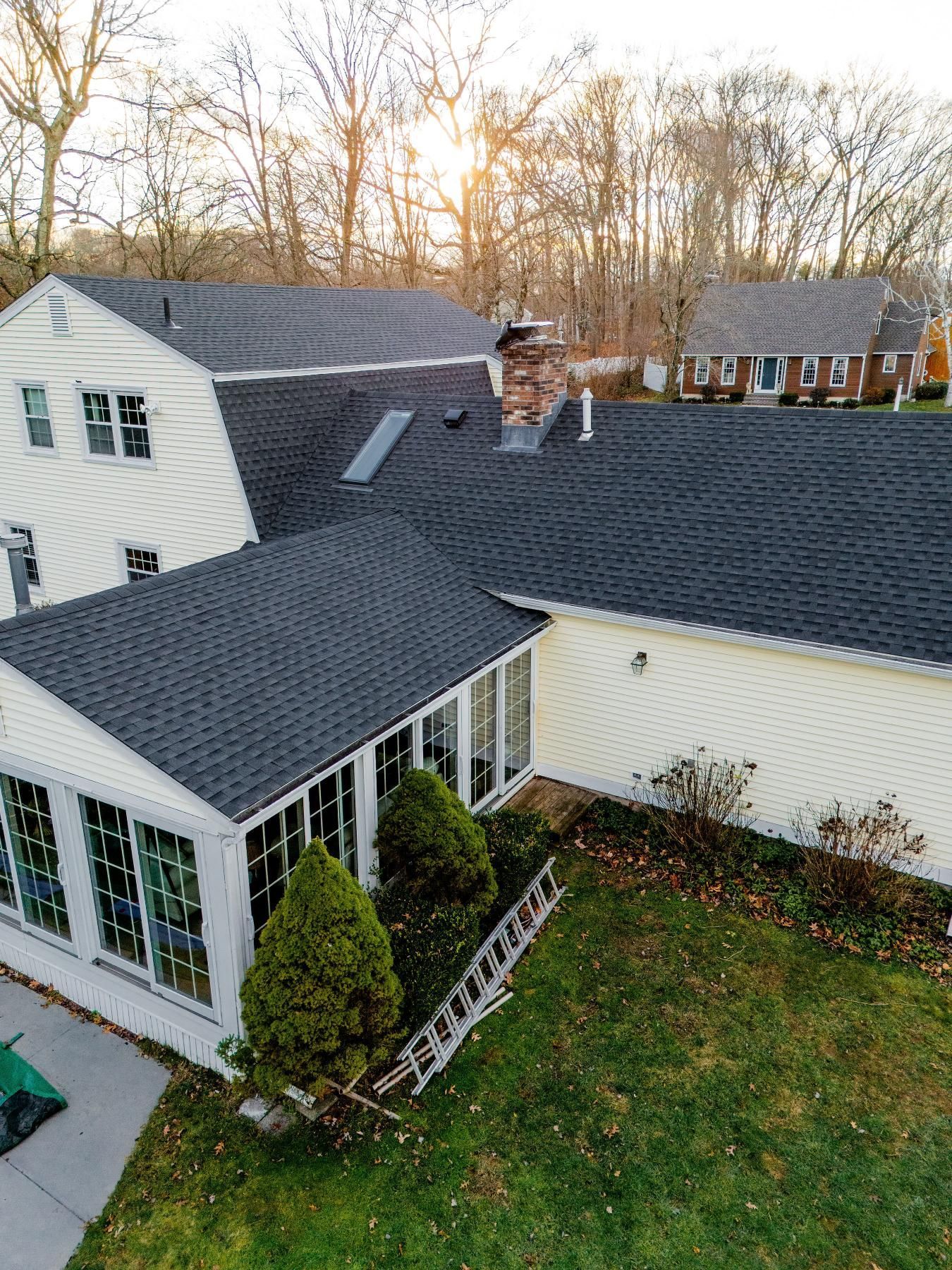 A house with a dark roof and a sunroom, with trees in the background.