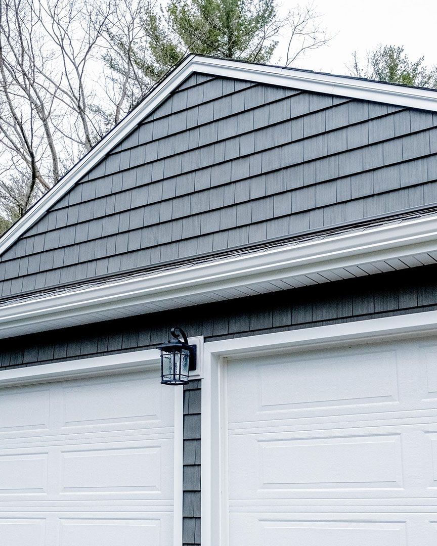 Garage with gray siding, white doors, and a decorative light.