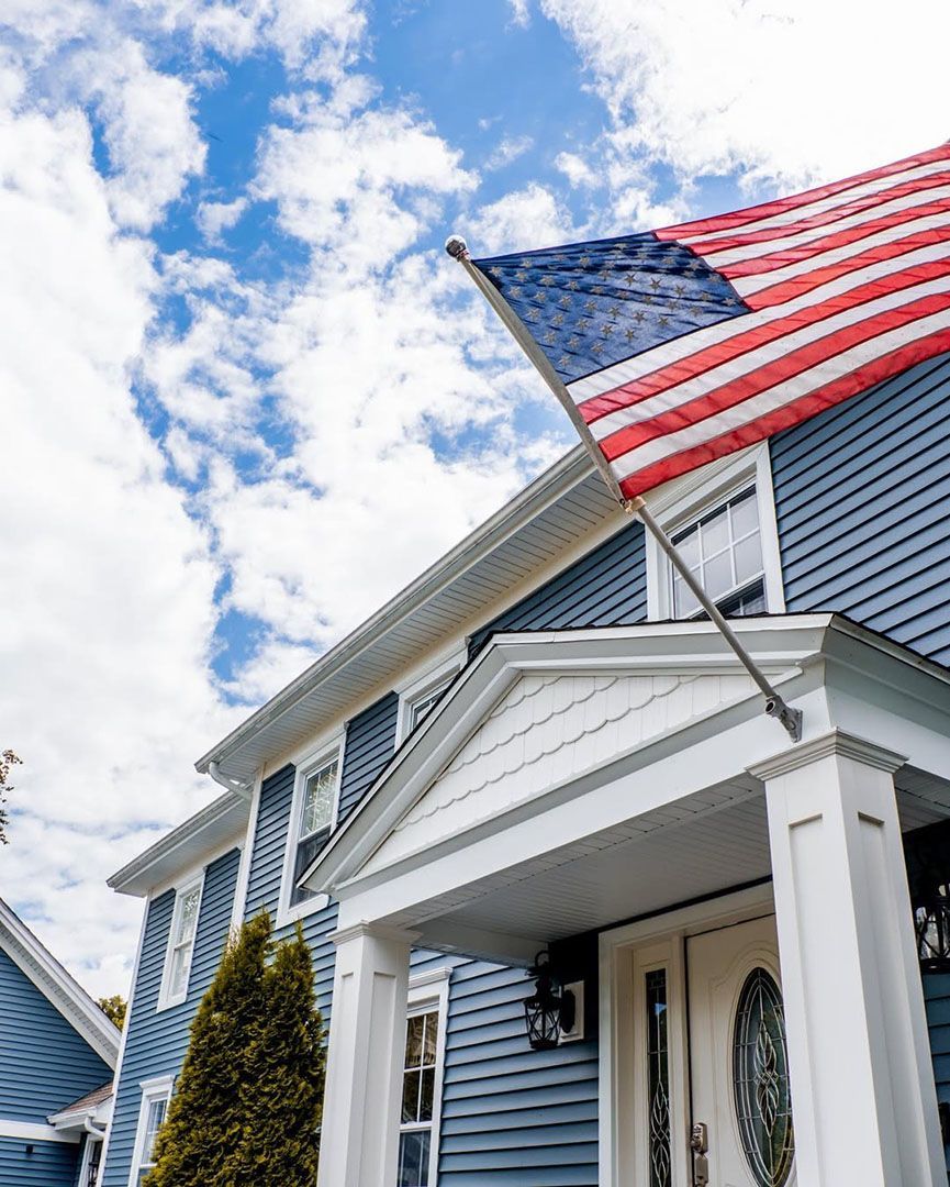 Blue house with American flag waving against a cloudy sky.