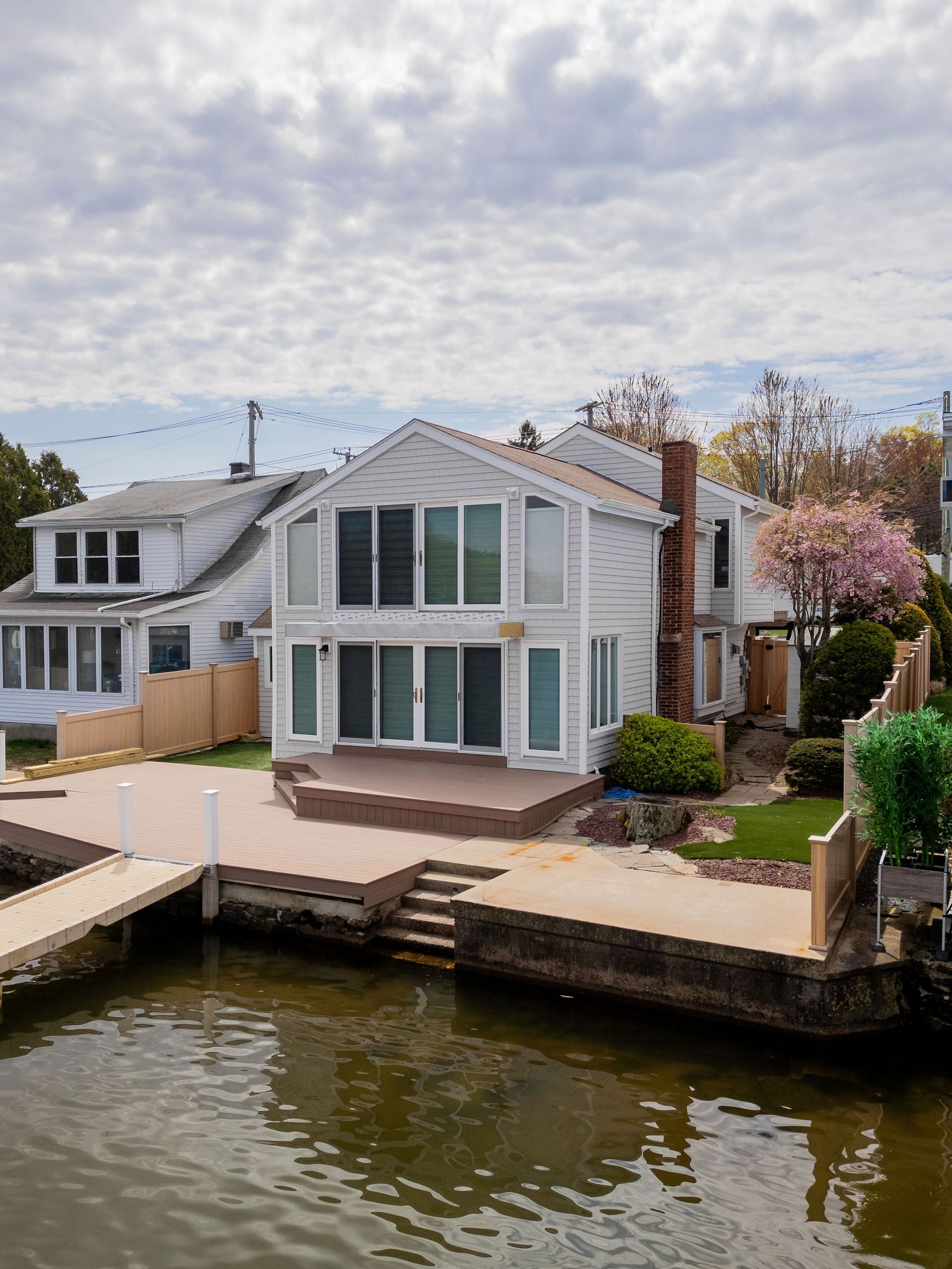 Waterfront house with deck and dock on a cloudy day.