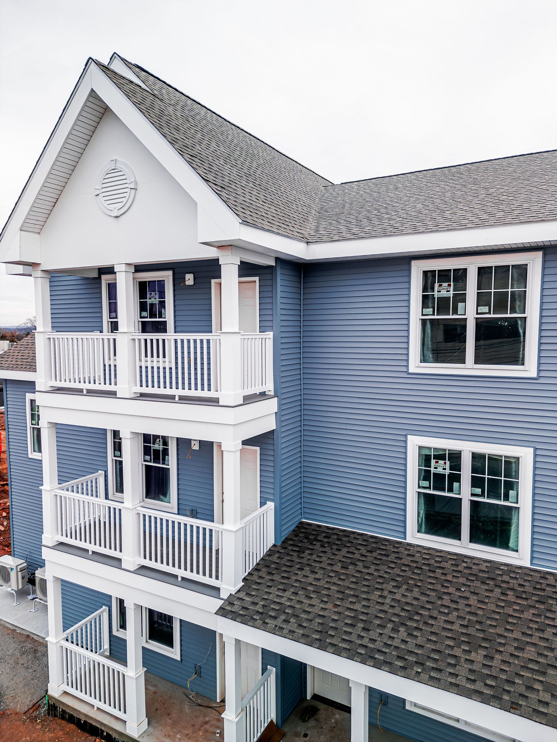 Blue building with white balconies and a gray roof, cloudy sky.