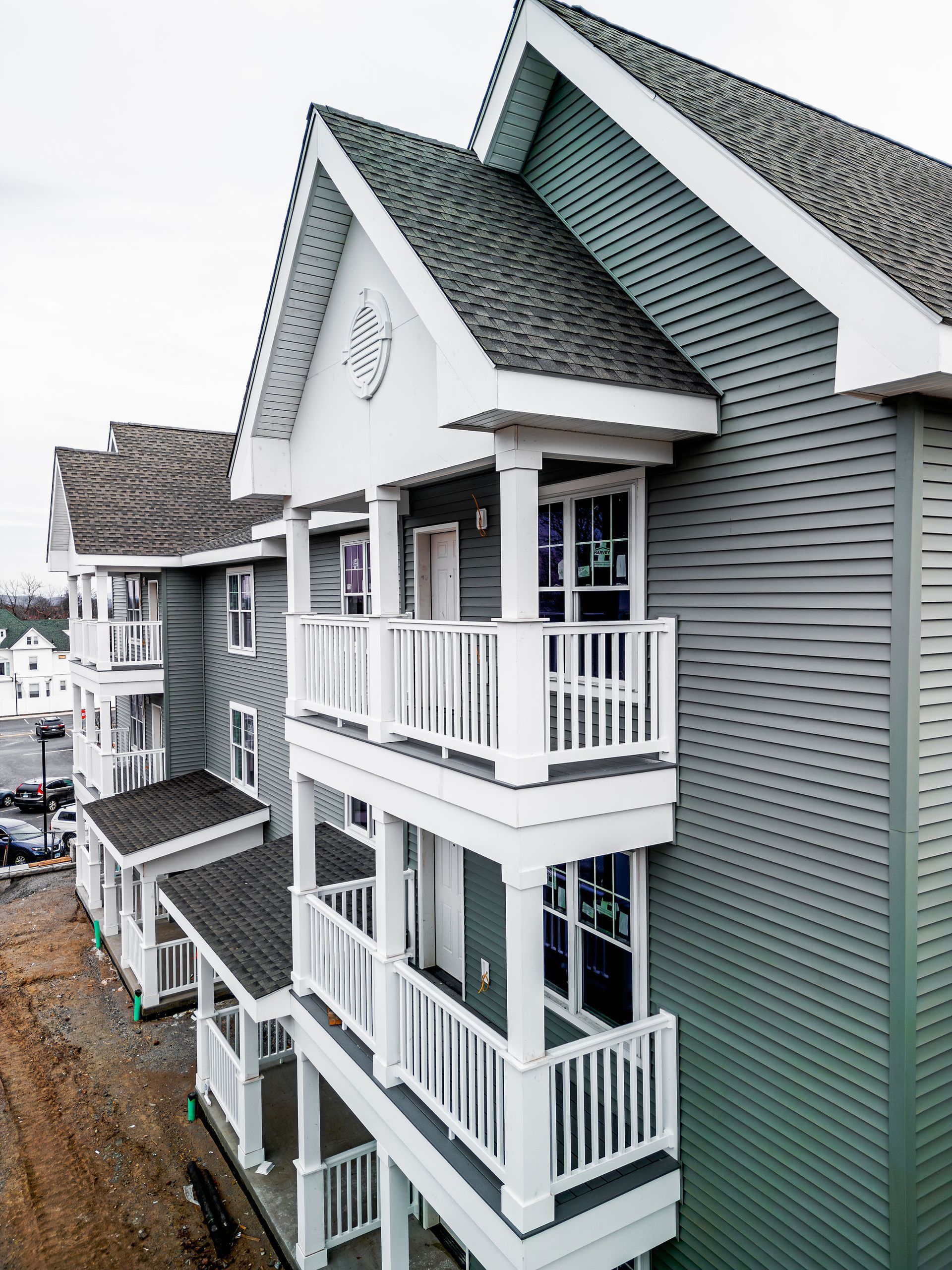 Multi-story apartment building with green siding and white balconies under a gray sky.