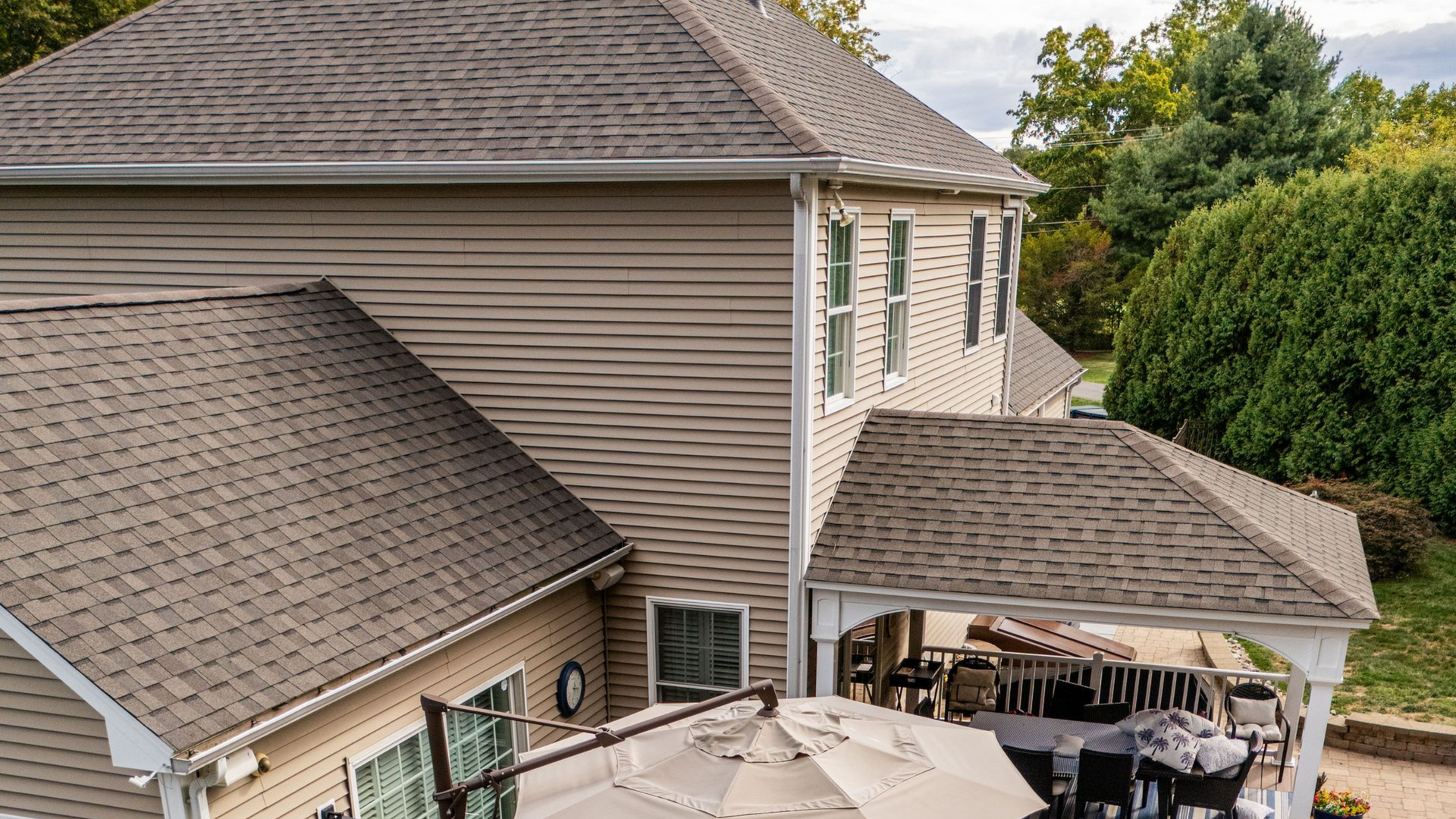Exterior view of a house with brown roofs and siding, outdoor deck with patio furniture.