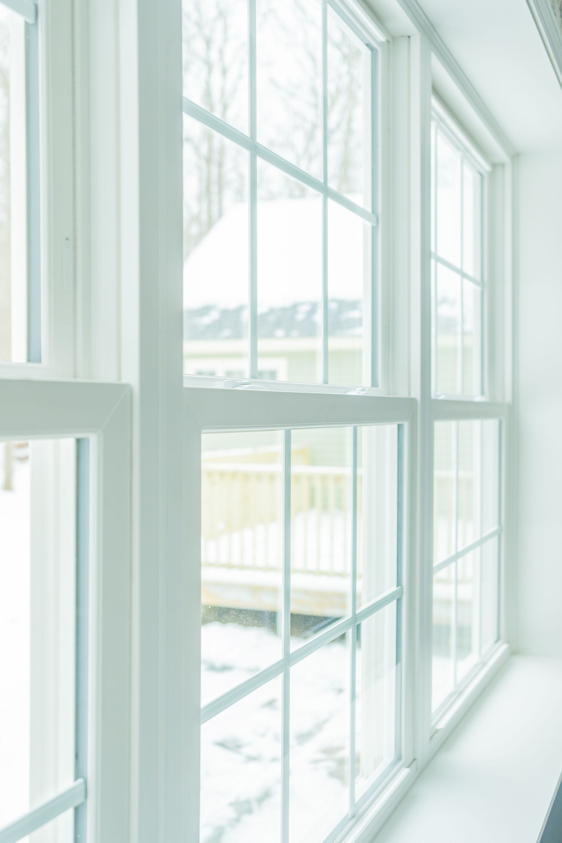 White window panes with grid patterns overlooking a snowy outdoor scene.