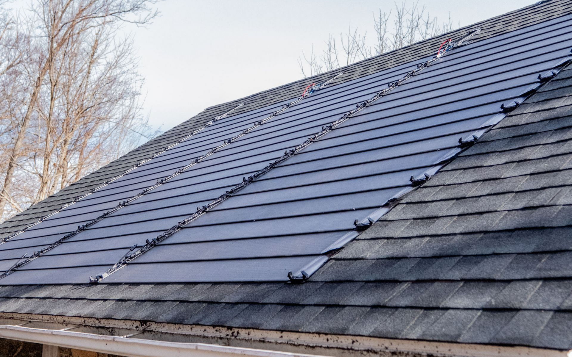 Partially repaired roof with dark shingles and exposed underlayment on the right side