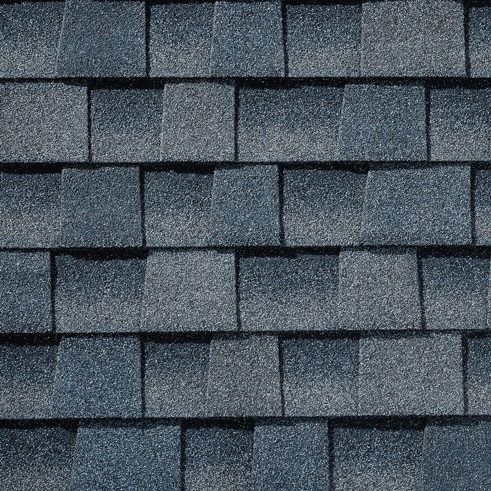 Close-up view of layered, dark blue and gray asphalt roof shingles.