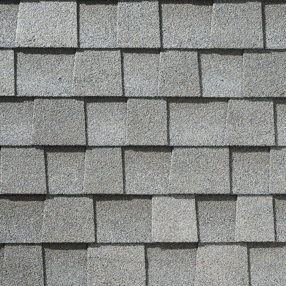 Gray asphalt shingles, overlapping, covering a roof.