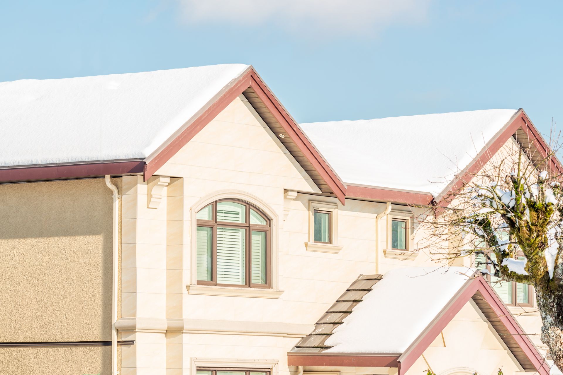 White house with snow-covered roof against a light blue sky.
