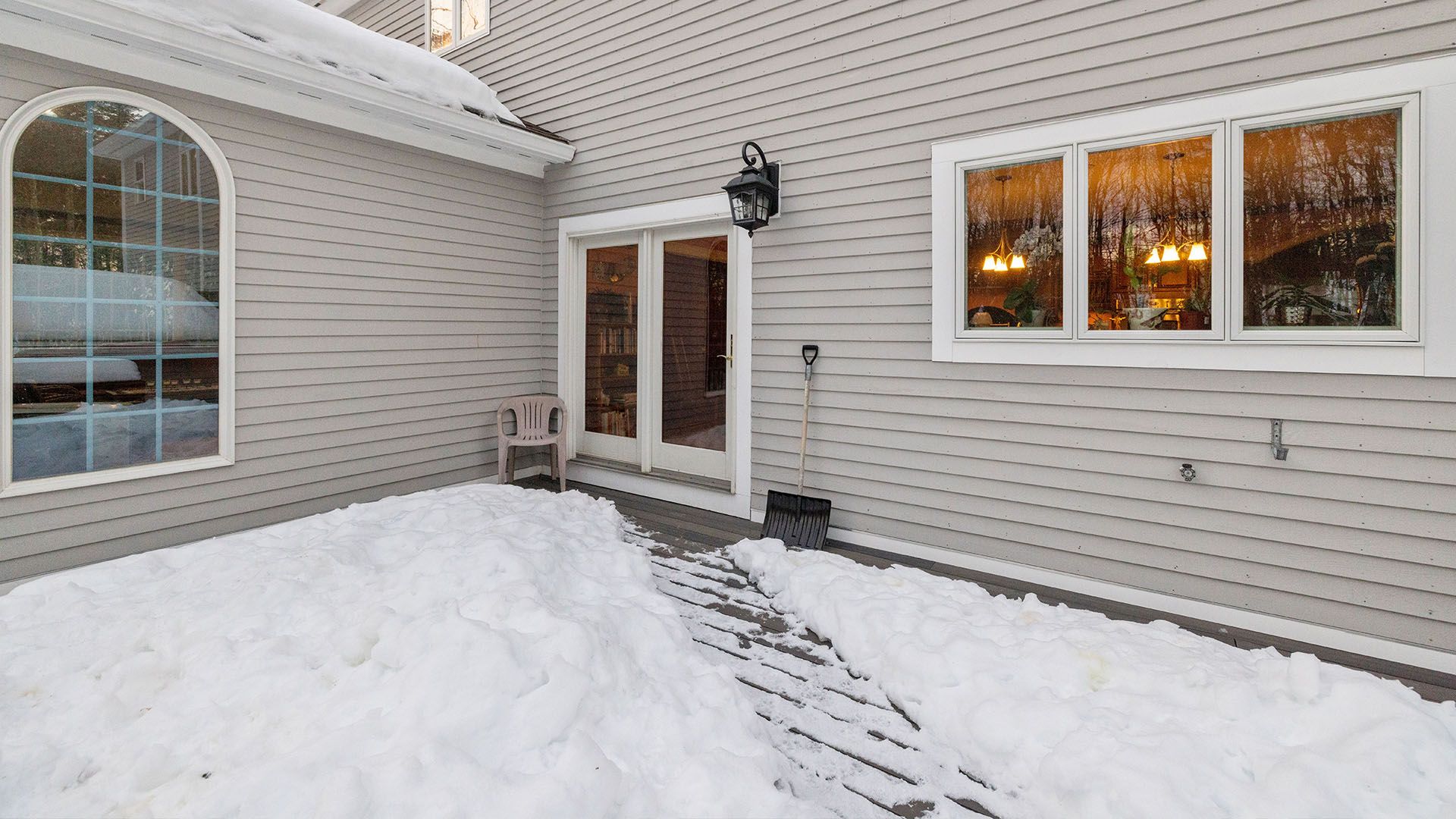 Exterior of a house covered in snow with a shoveled pathway leading to a doorway.
