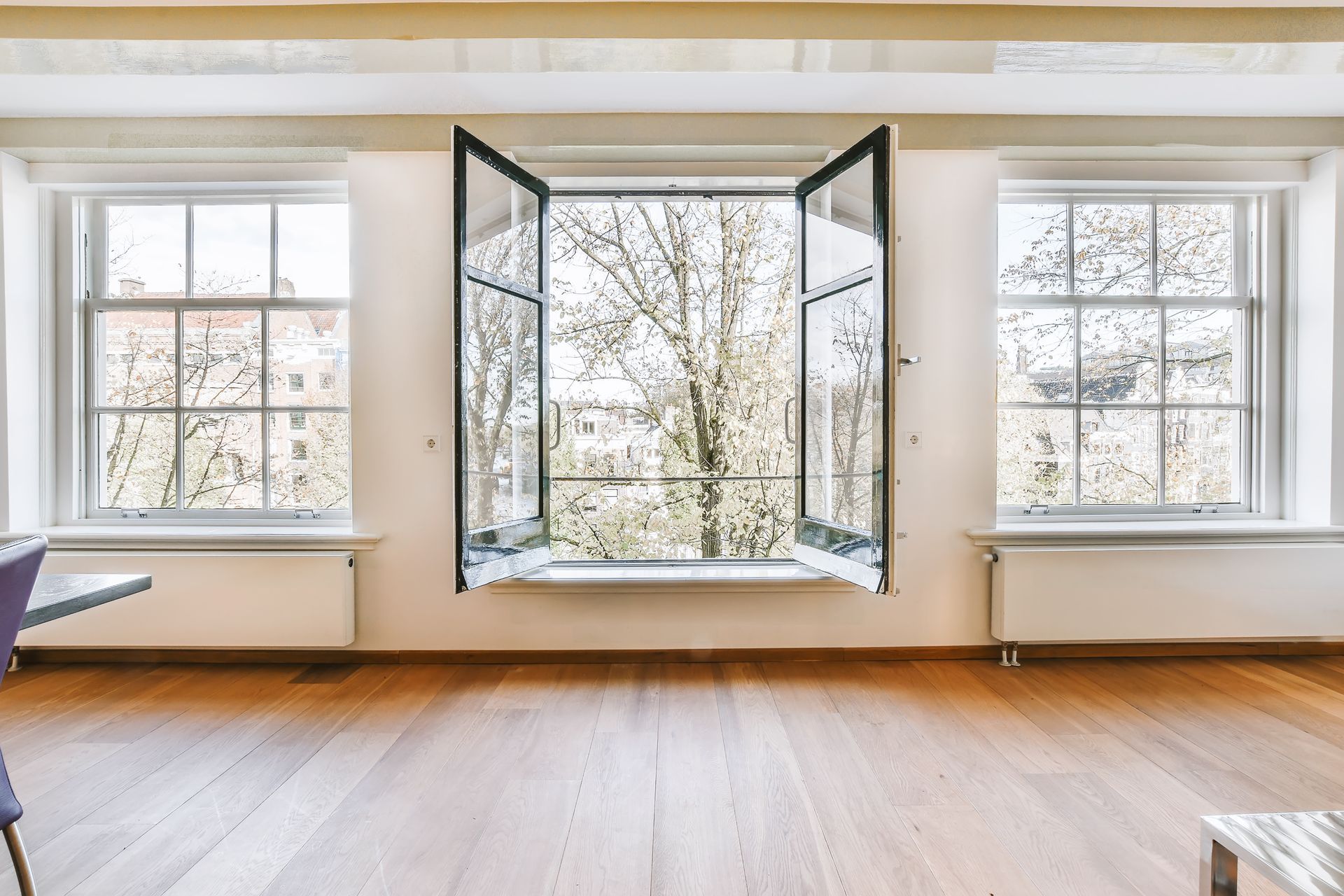 Bright room with open central window, two closed side windows, and hardwood floors.