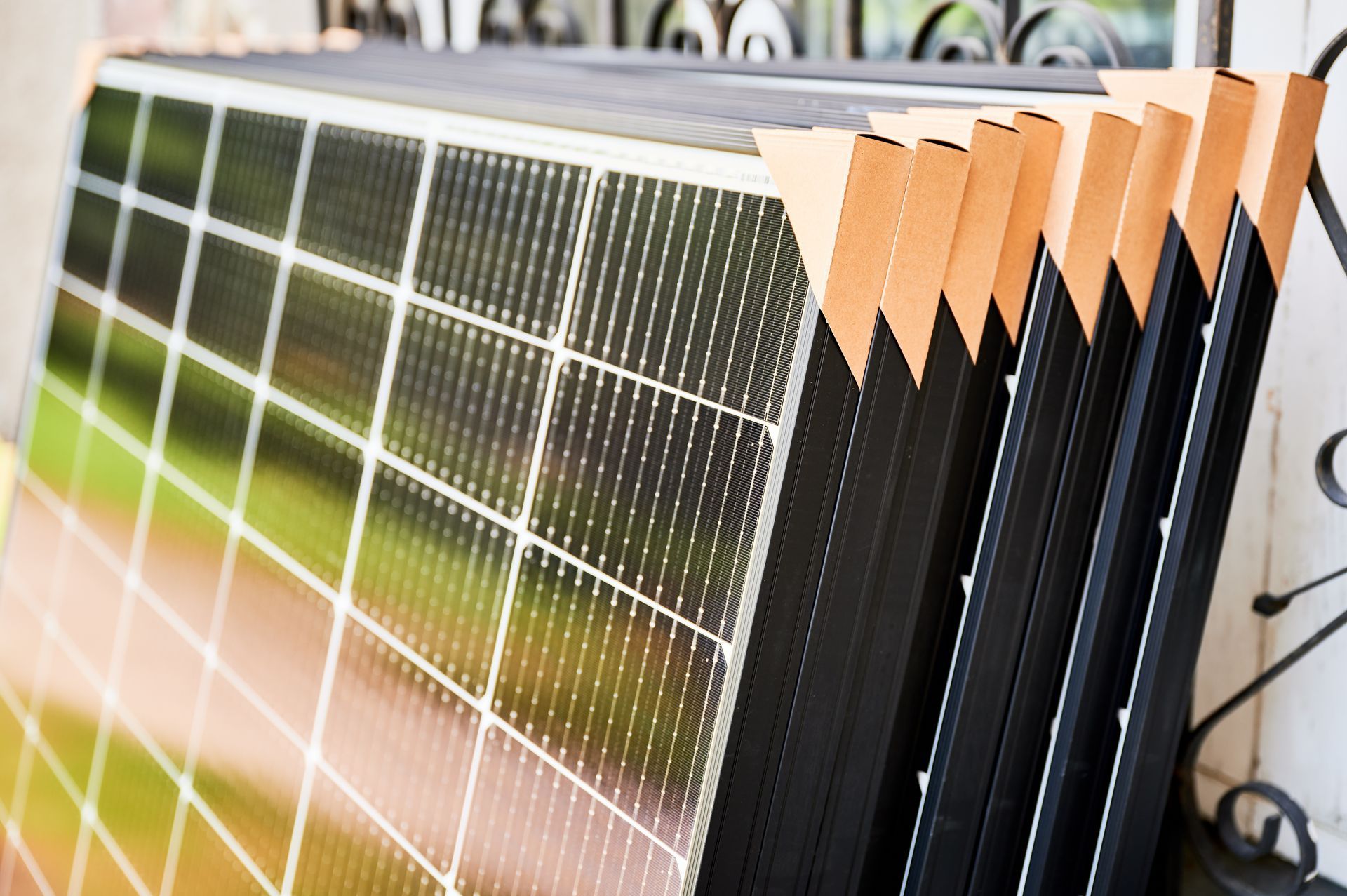 Row of solar panels leaning outdoors, with black frames and reflective glass surfaces.