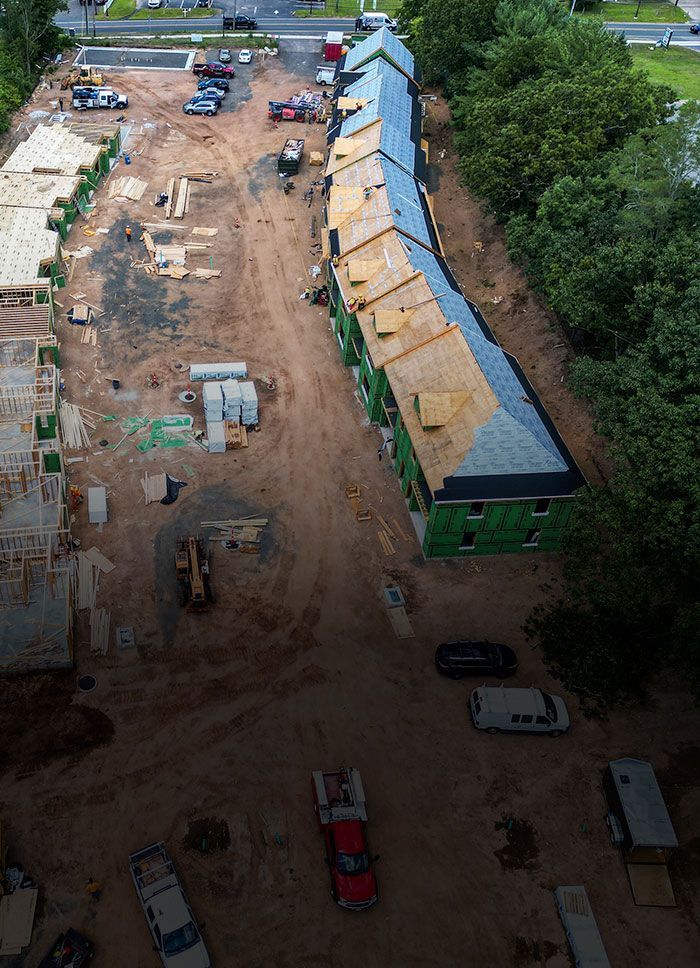 Aerial view of construction site with multiple buildings, some framed and others with roofing.