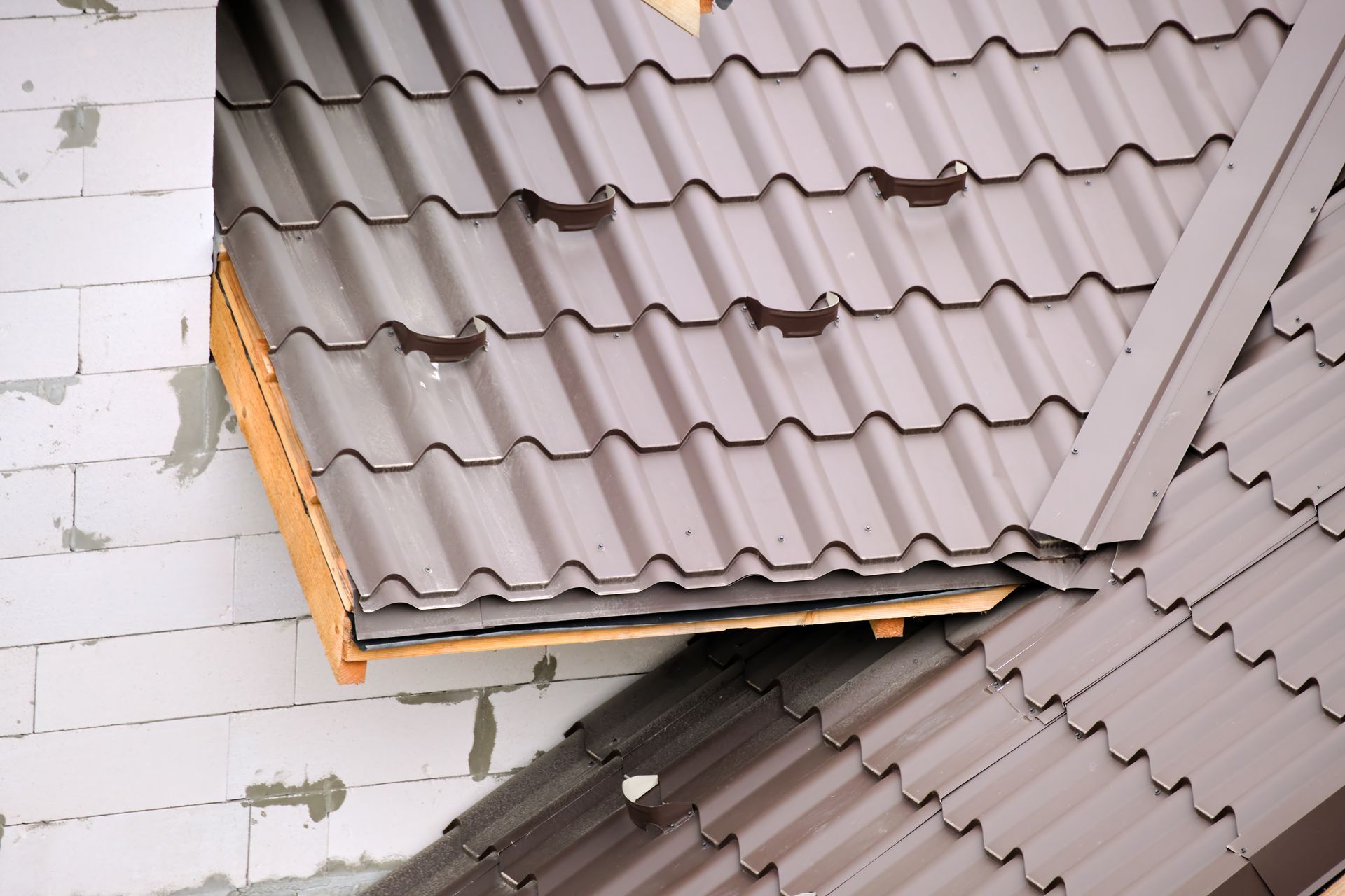 Damaged gray roof with missing shingles and a collapsed section over a white brick wall