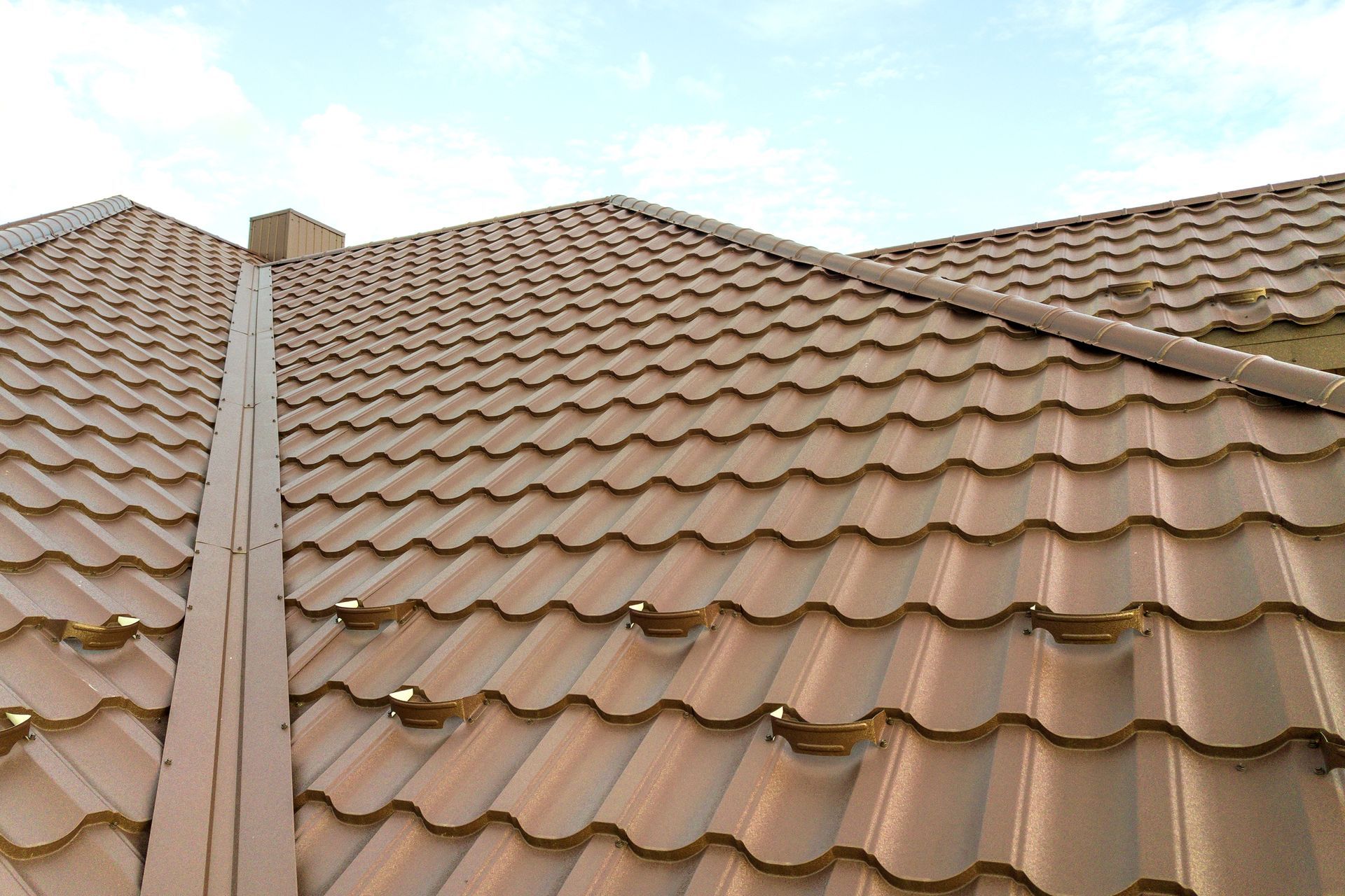Brown tiled roof with skylights under a blue sky