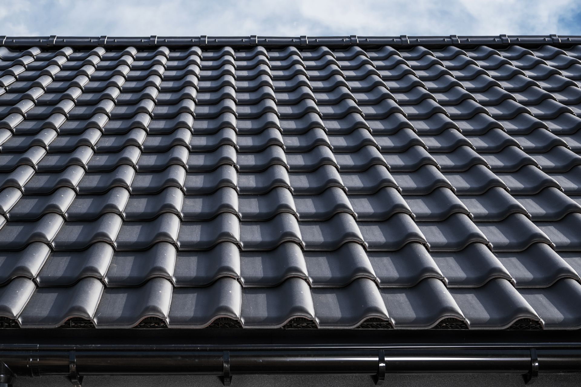 Dark gray tiled roof with repeating curved shingles