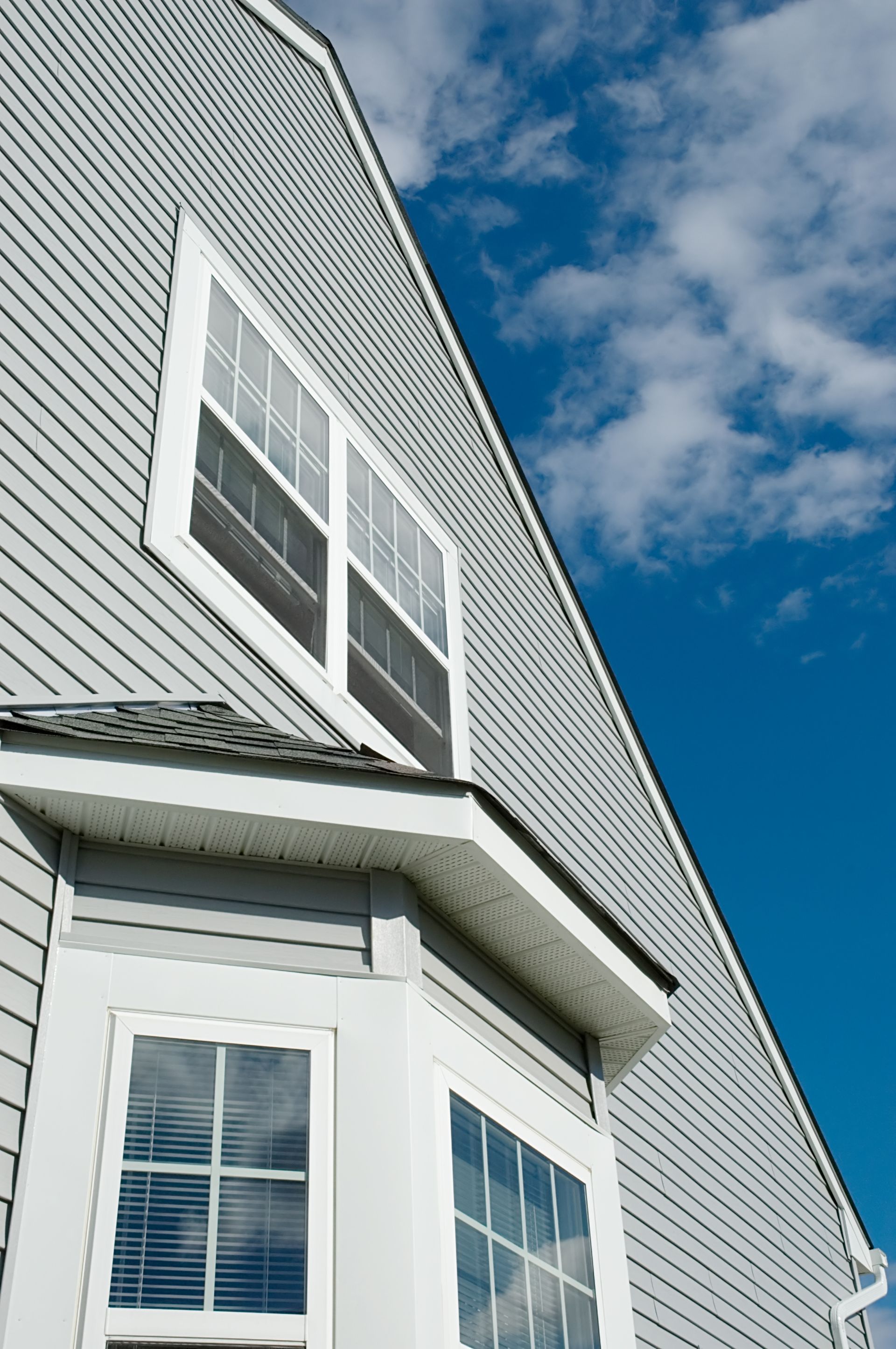 White house siding and bay windows under a blue sky