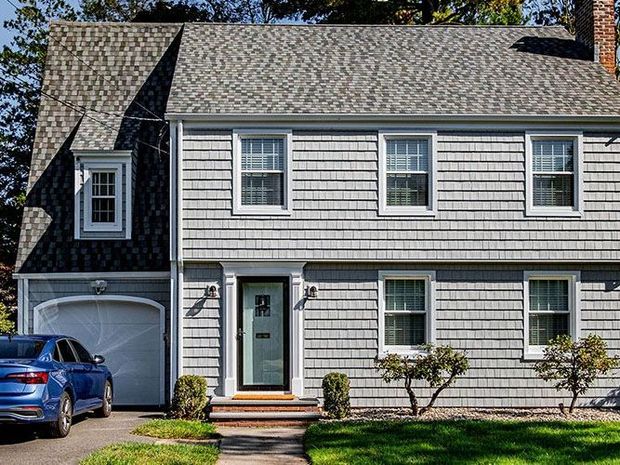 Two-story gray house with a blue car parked in the driveway.