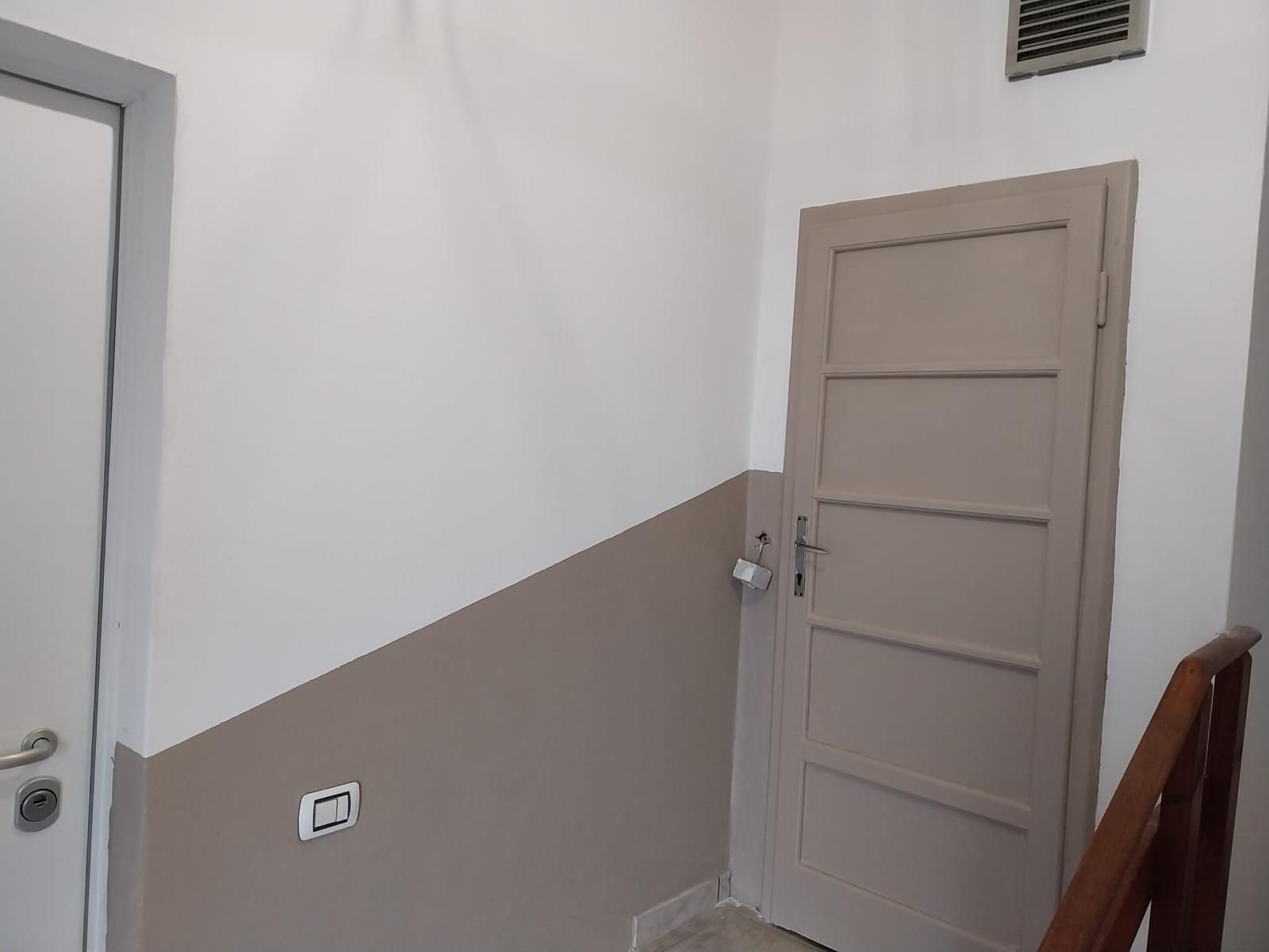 Un corridoio con una porta beige chiusa e pareti bicolore (beige e bianco).