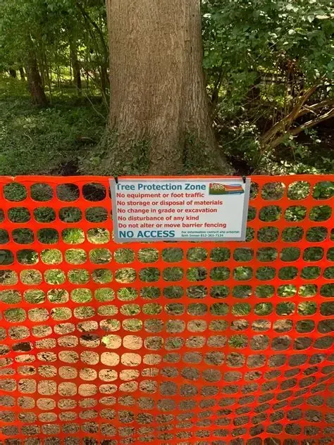 Orange safety fence with “No Access” sign in front of a tree in a wooded area