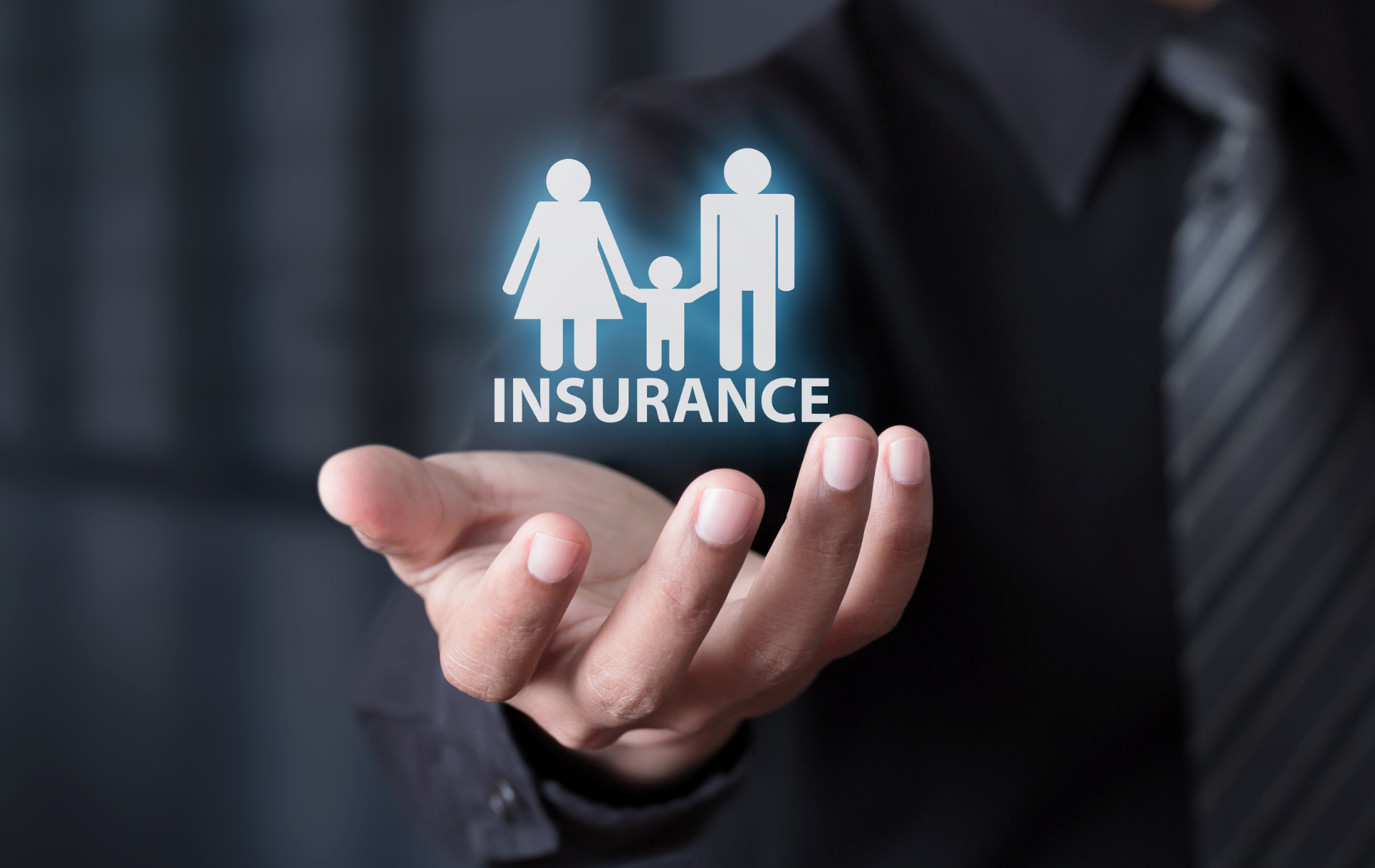Hand holding glowing insurance icon with family symbol and umbrella text on dark background