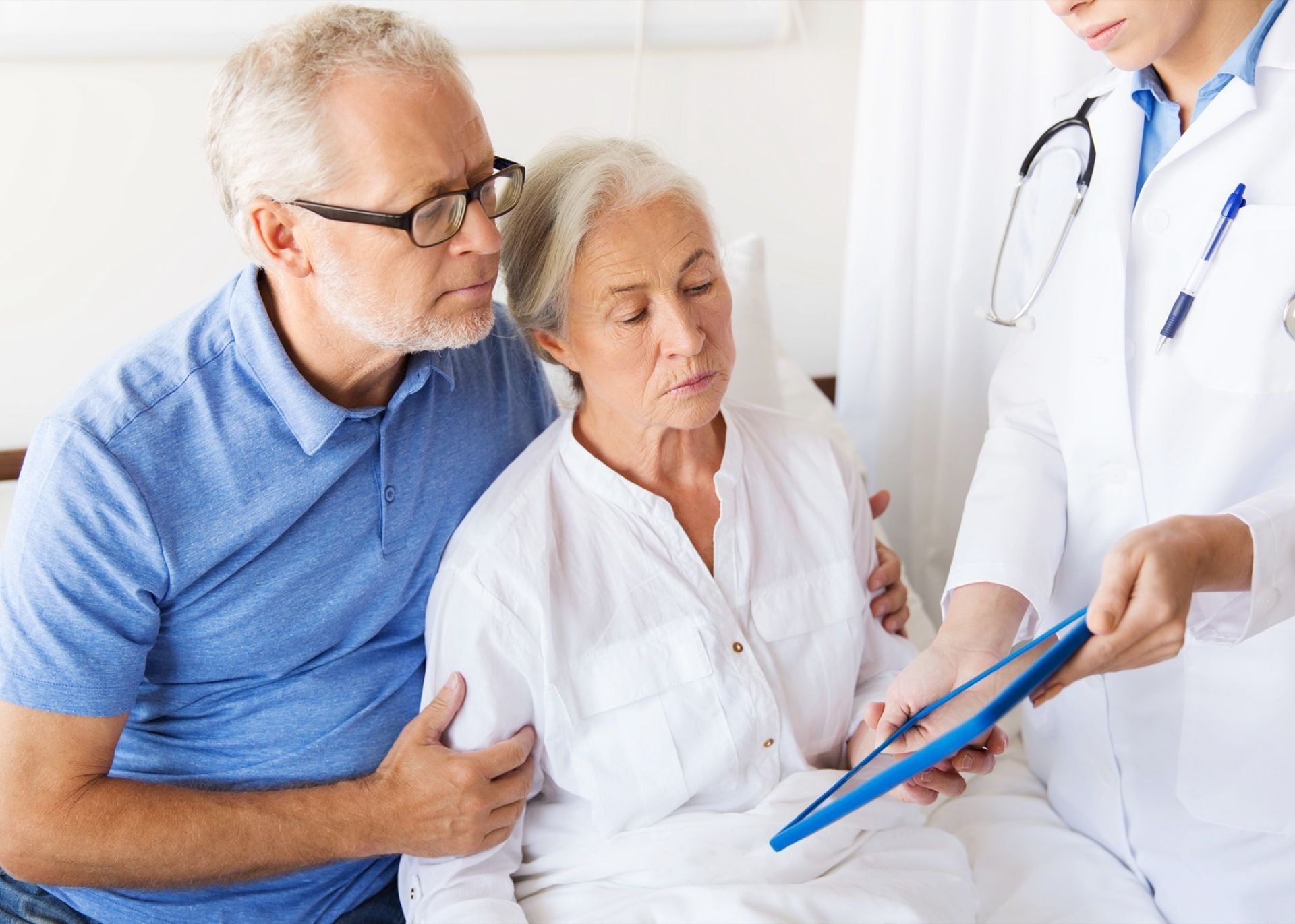 Doctor showing chart to seated couple in a bright clinic room