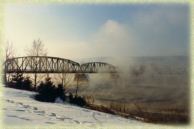 A bridge over a body of water with snow on the ground