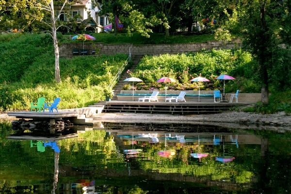 A dock with chairs and umbrellas is reflected in the water.