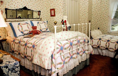 A bedroom with two beds and a teddy bear on the bed