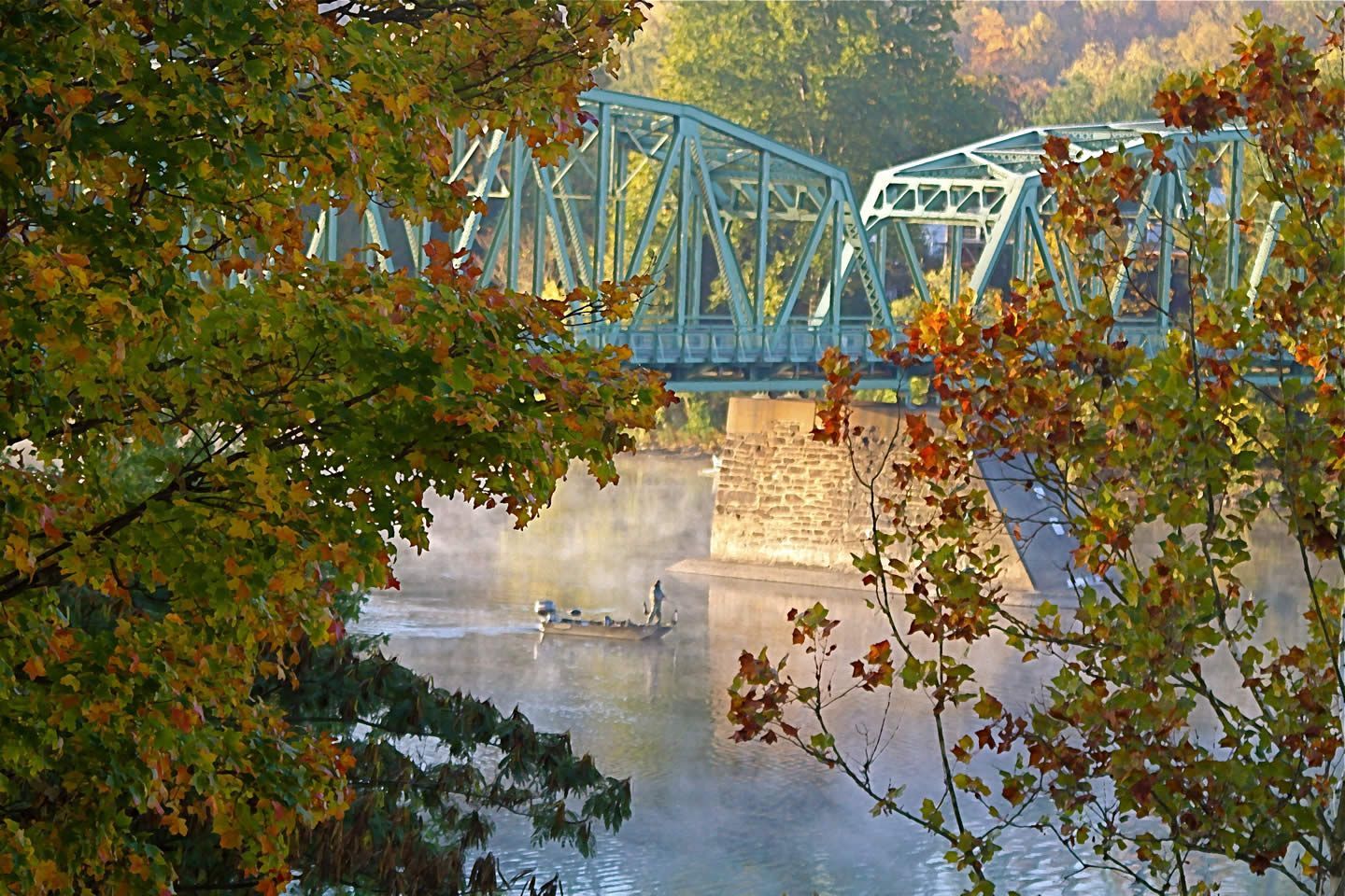 A bridge over a river with trees in the foreground