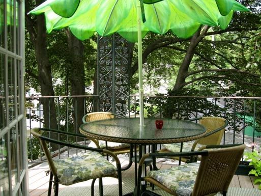 A green umbrella is hanging over a table and chairs