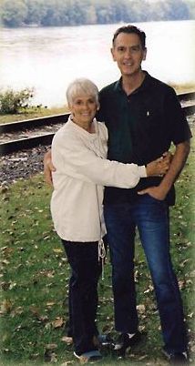 A man and a woman are posing for a picture in front of a body of water.