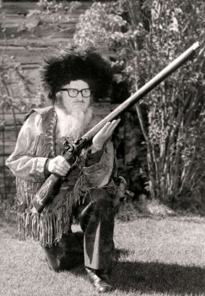 Buckskin Bill holding a long rifle outdoors