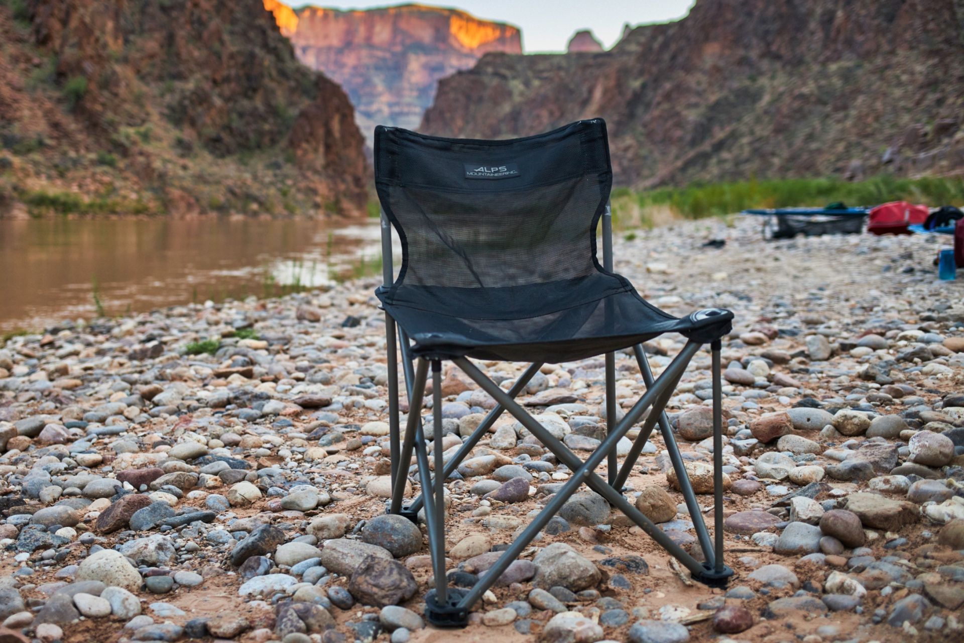 Folding camp chair on a rocky beach beside the river