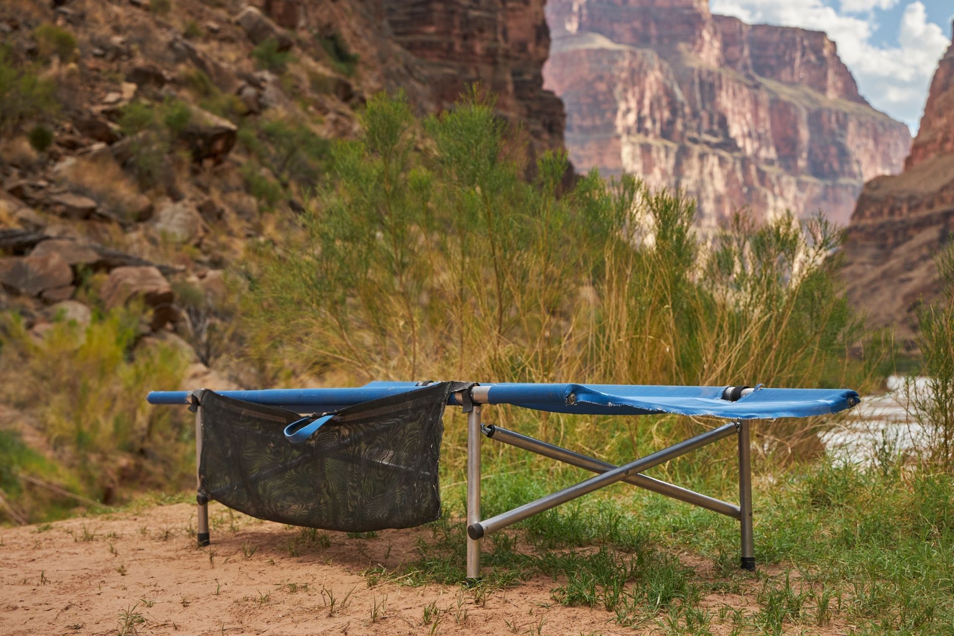 Raised camping cot set beside a tent in a canyon camp